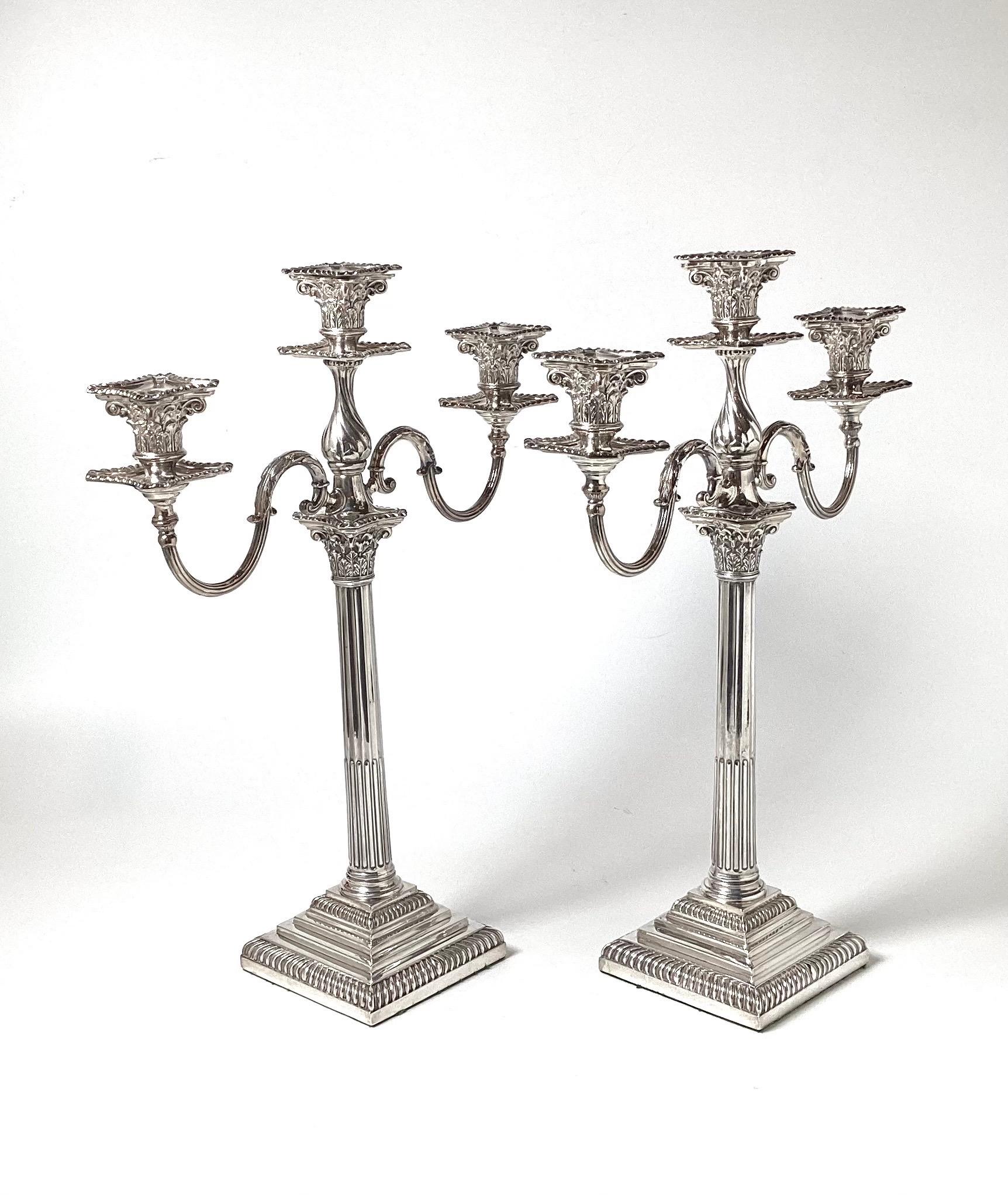 An elegant pair of three light silver plate neoclassical column style candelabra.  The center ribbed column with removable tops for three candles.  The pair with their original bobeches.  The bottoms with felt for protection of the table.  These are