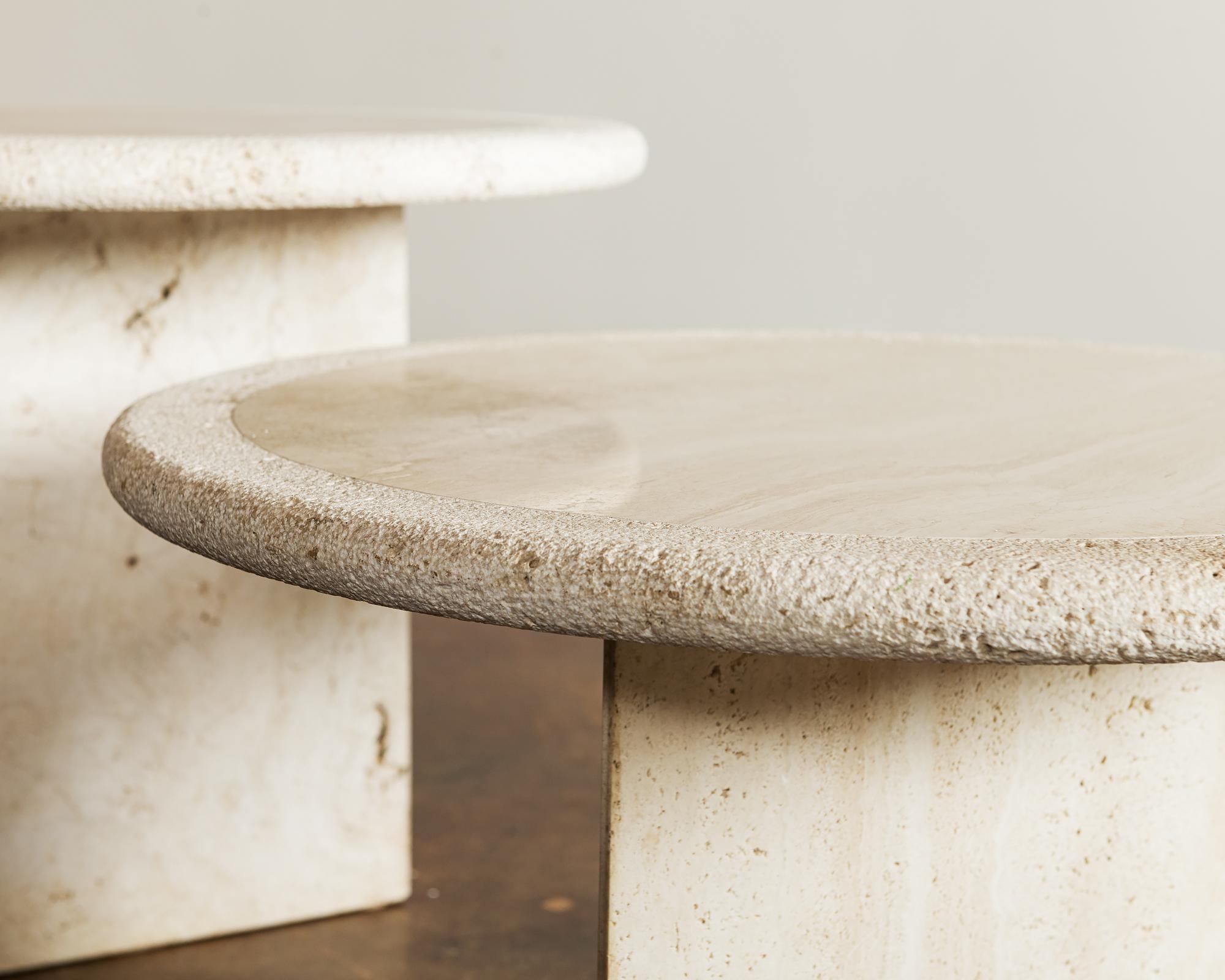 Pair of modern travertine coffee tables on triangular pedestal bases. 

Each table top is 24 inches in diameter with bases of 17 and 13 inches.