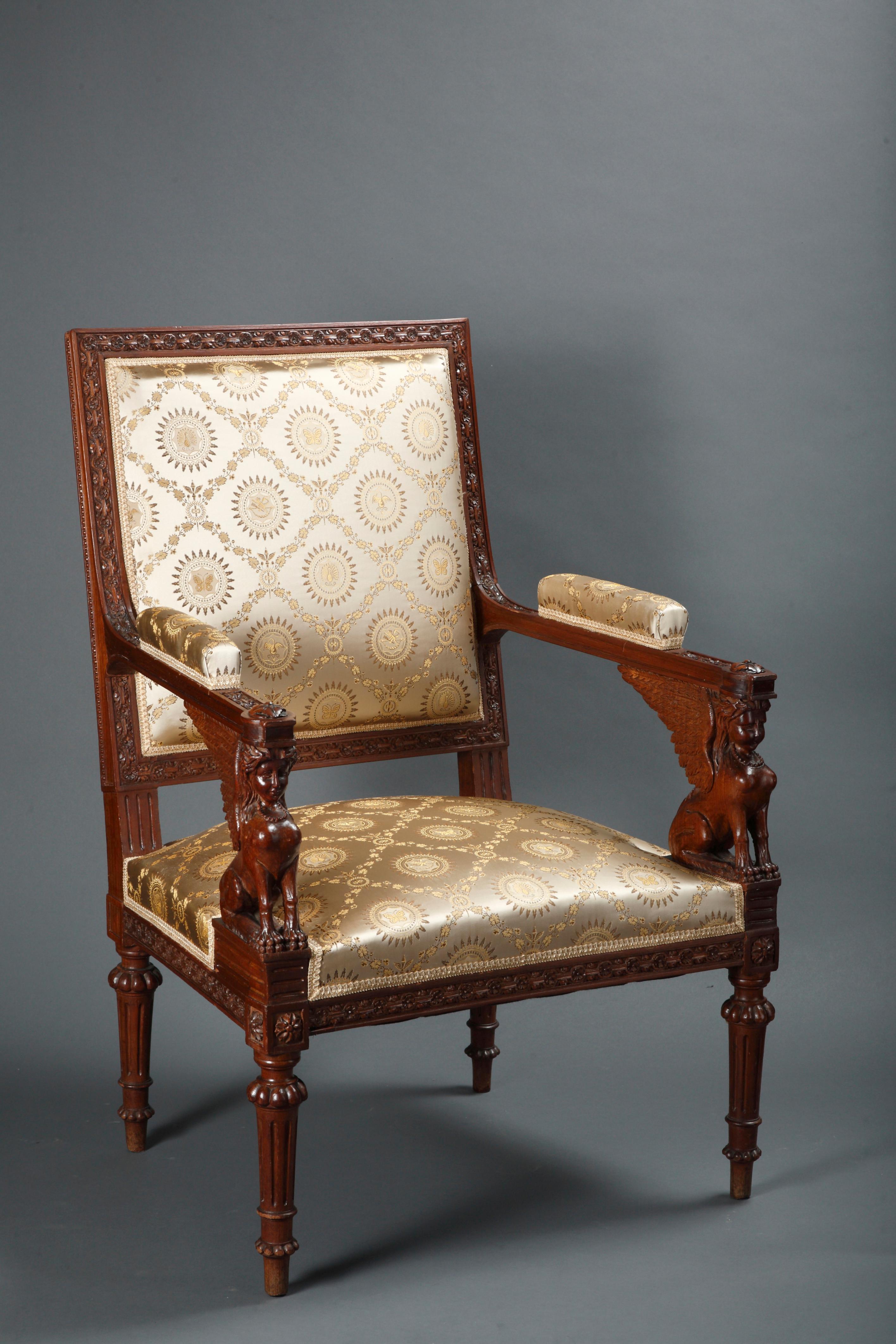 A very fine pair of carved and tinted wood armchairs after G. Jacob, with carved sphinges for the armrest supports. The circumference of the seatback and the seat belt are delicately carved with beads, rosettes and links. Reposing on tapered and