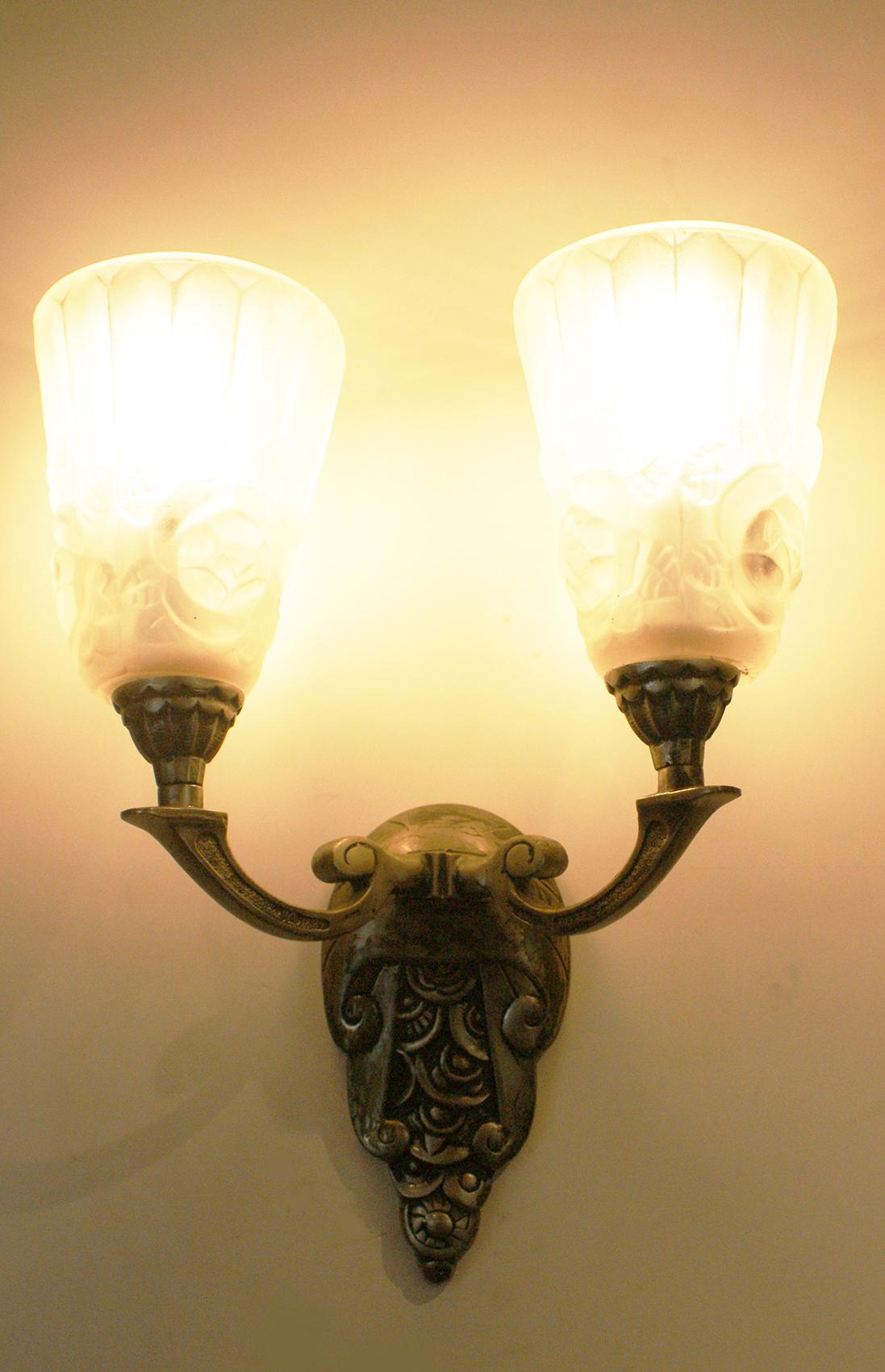 A decorative pair of French Art Deco wall sconces signed “Degué ” consists of a nickel bronze structure with beautiful floral motif design in the central of the sconces and two arms supporting two tulips in molded clear frosted glass, each tulip is