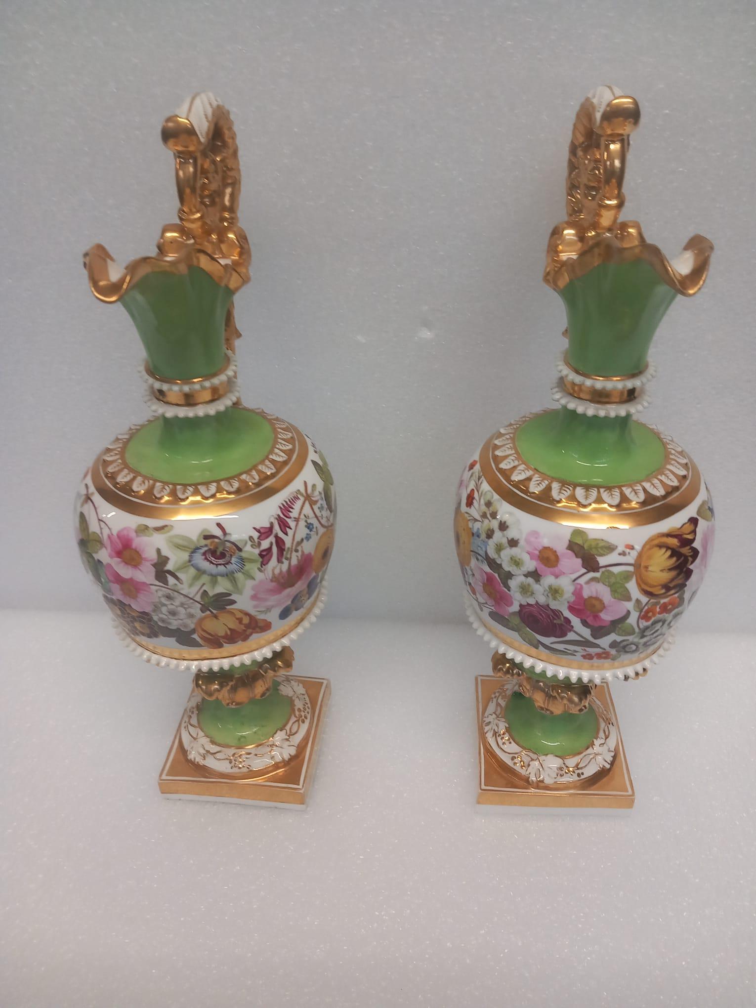 A wonderful pair of early nineteenth century porcelain urns probably made by either Coalport or Minton circa 1810.
The elaborate gilded handles add a touch of extra elegance to an already beautiful pair of urns or vases. The lips are scalloped and