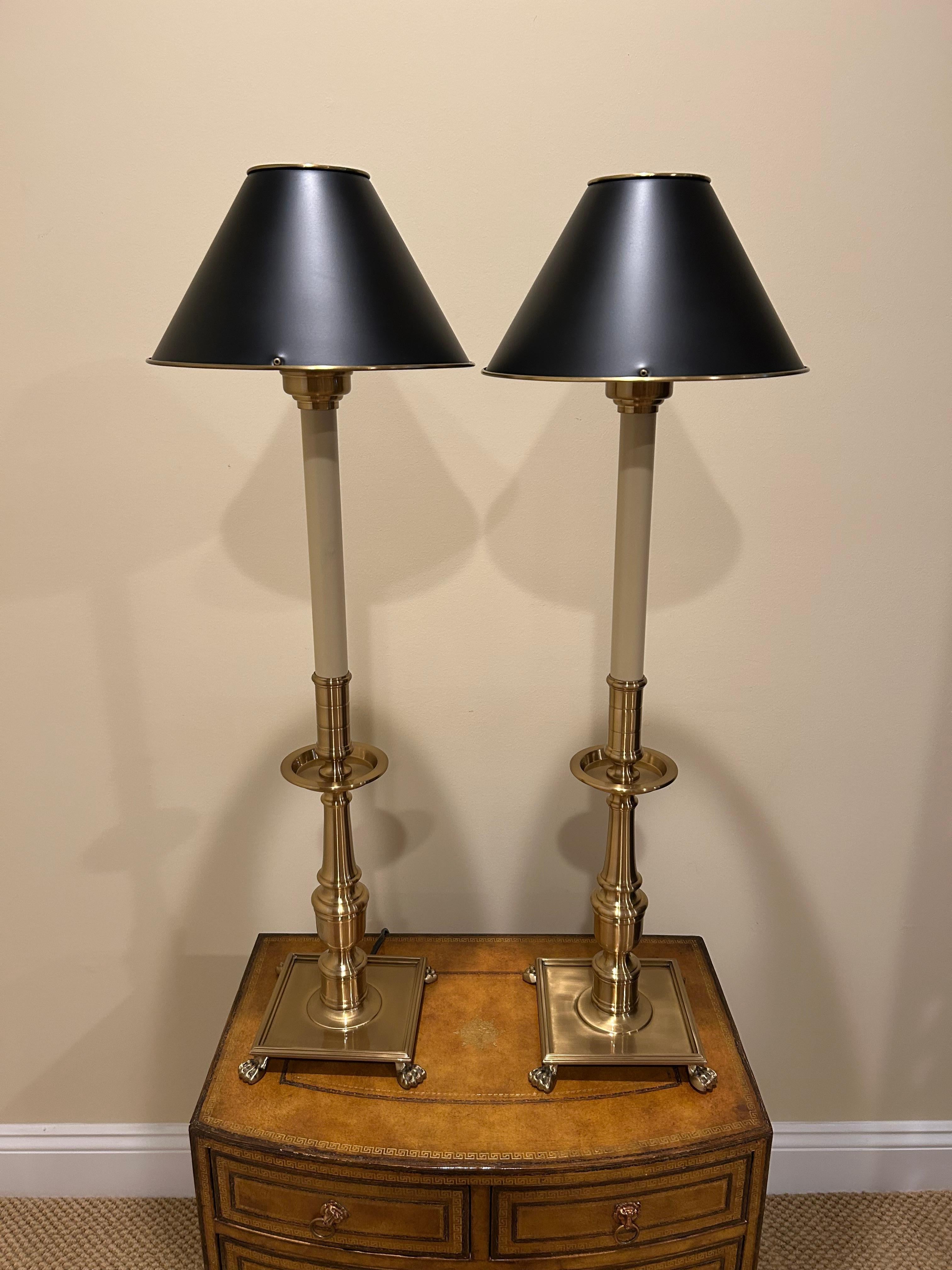 Elegant tall brushed brass table lamps having small black metal shades.  Bases are square with lovely detailed feet.