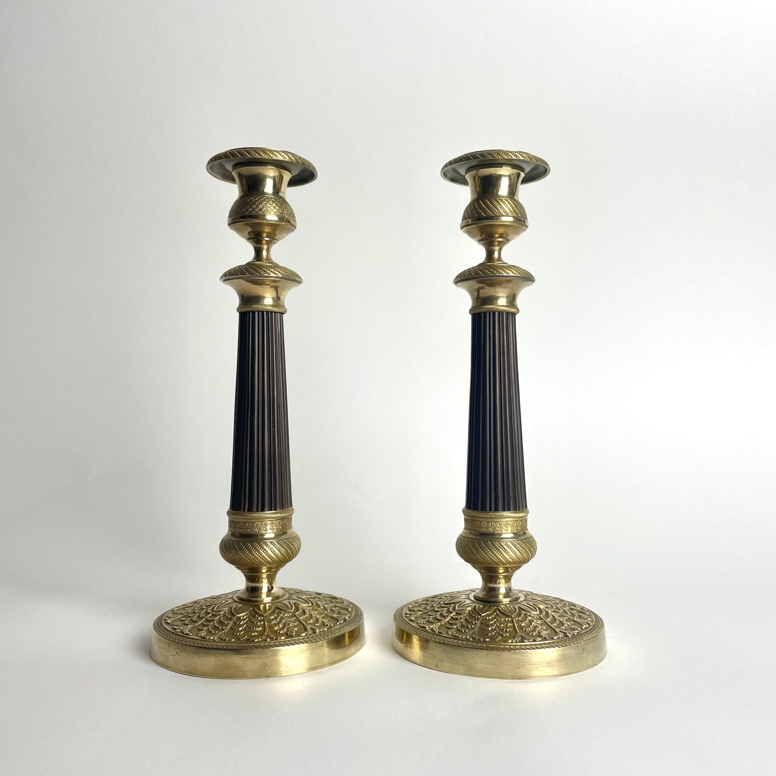 Elegante pareja de candeleros Imperio en bronce dorado y patinado oscuro. 1820s Francés en venta