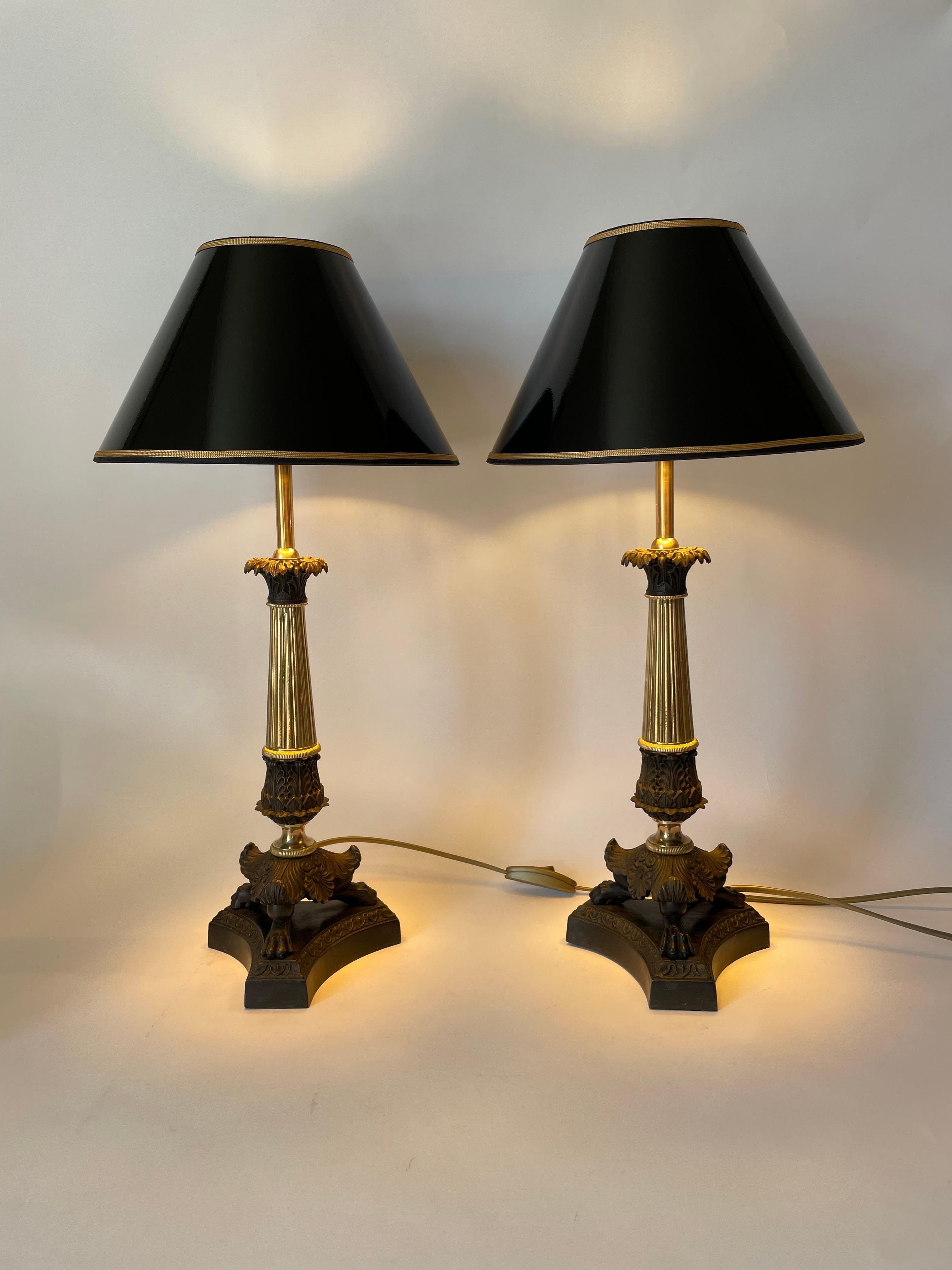 Elegant pair of Empire Table Lamps in gilt and dark patinated metal. Originally a pair of Empire candelabra from the 1830s, converted to tablelamps in the early 20th Century.

Newly rewired electricity 

New lampshades in black lacquer with gilding