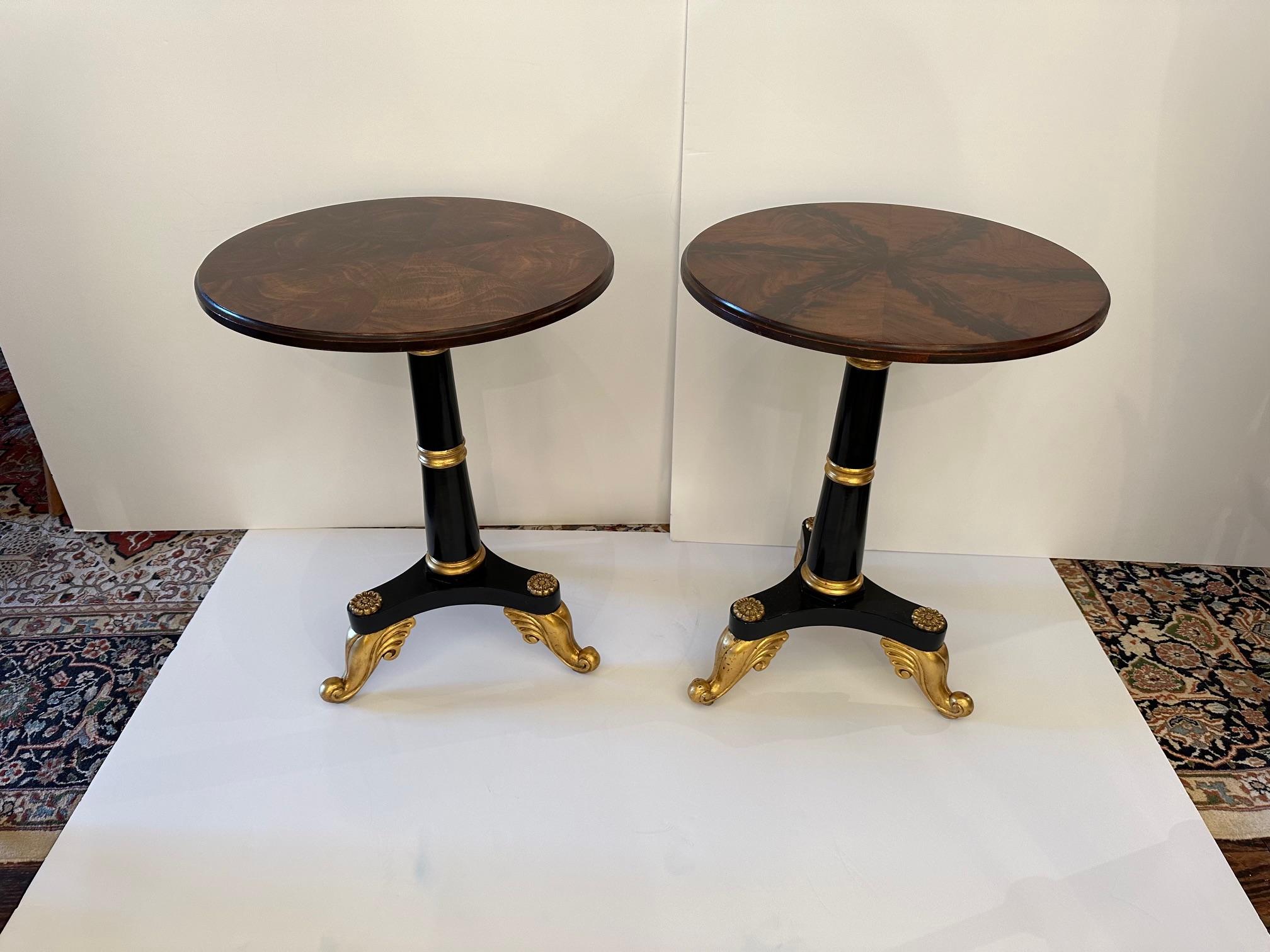 Sublimely elegant pair of round flame mahogany end tables having sumptuously grained tops that are unique in themselves, complimented by ebonized wood bases with gilded flourishes.
