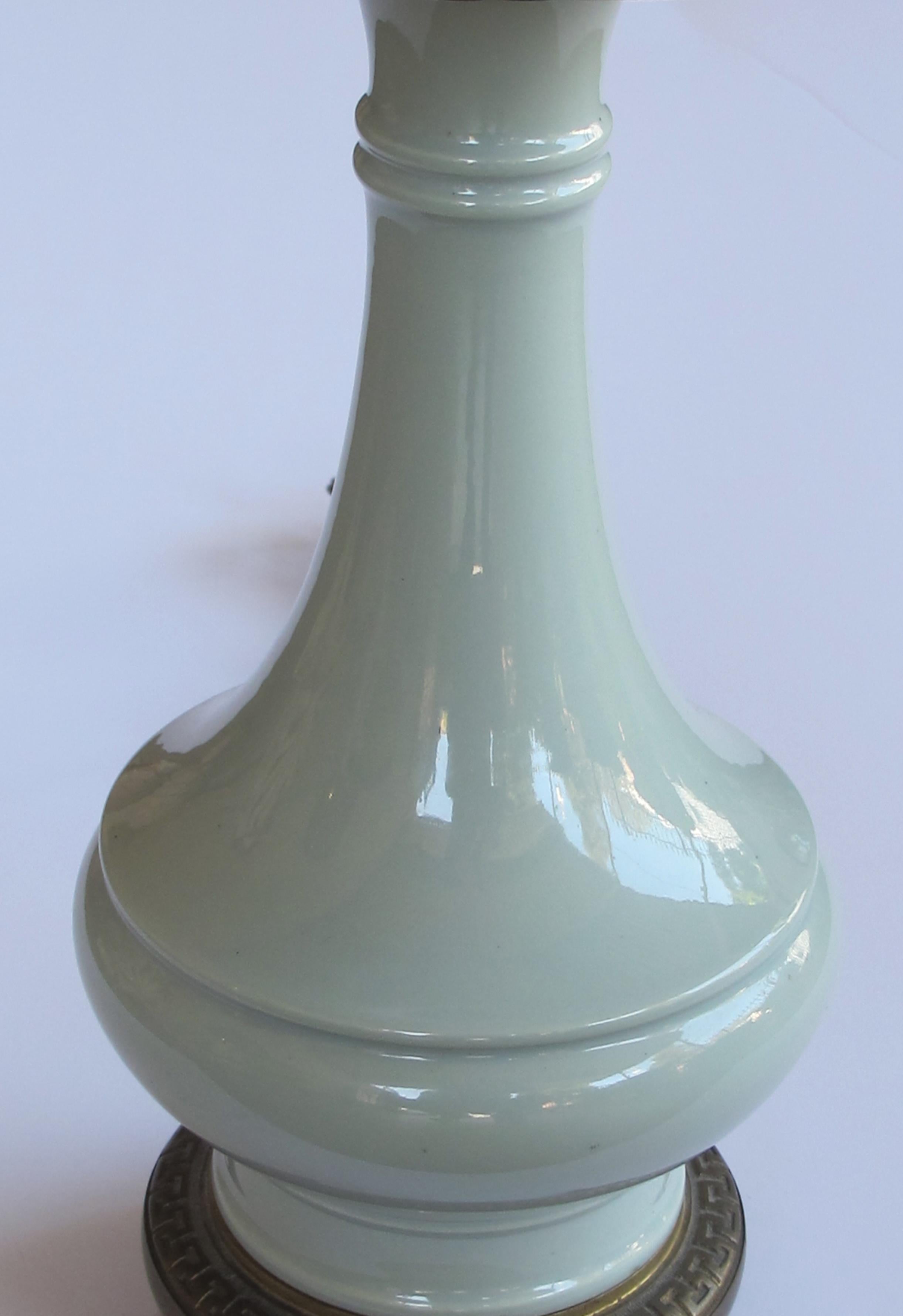 Each of bottle form in a soft sea-foam green celadon glaze; all raised on a brass base.