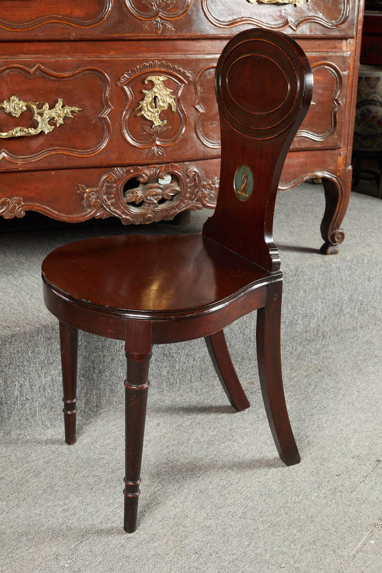 Elegant pair of Georgian period carved mahogany hall chairs the back decorated with a deer armorial crest.