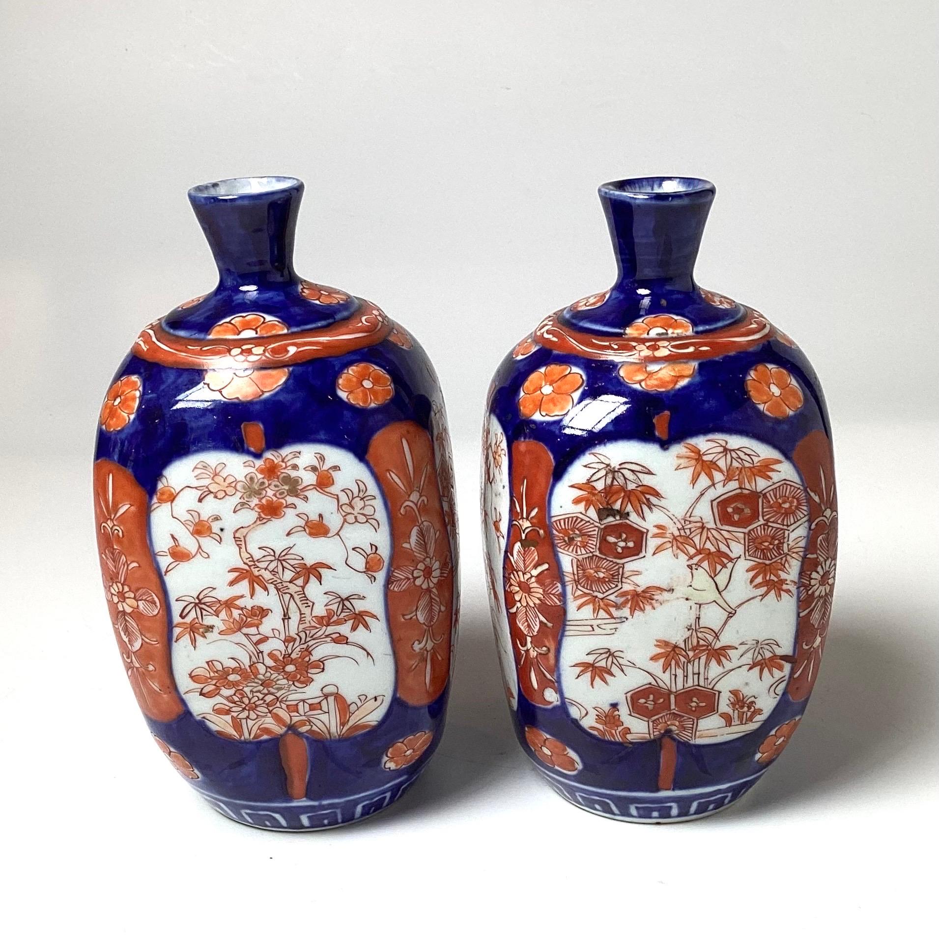 A pair of bulbous classic cobalt blue and iron red Imari vases.  The 7.5 inch tall vases with rounded bodies with small necks with had painted scenic views on each side, Japan, Circa 1880, Meiji Period