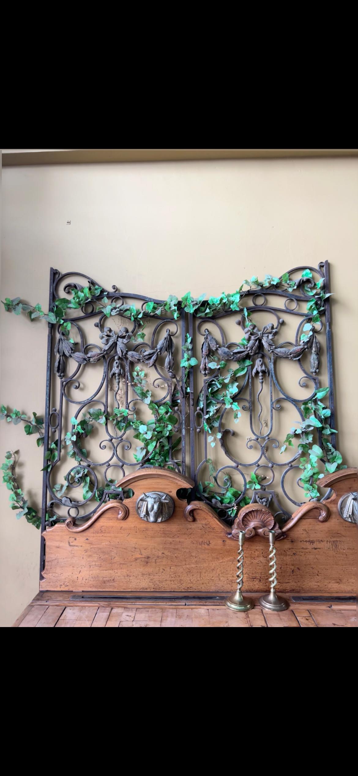Elegant pair of iron gates with detailed suspended swags, forged and hammered with a trace of gilt, two different patinas present. originates from France, circa 1890. Each gate measures 33.75