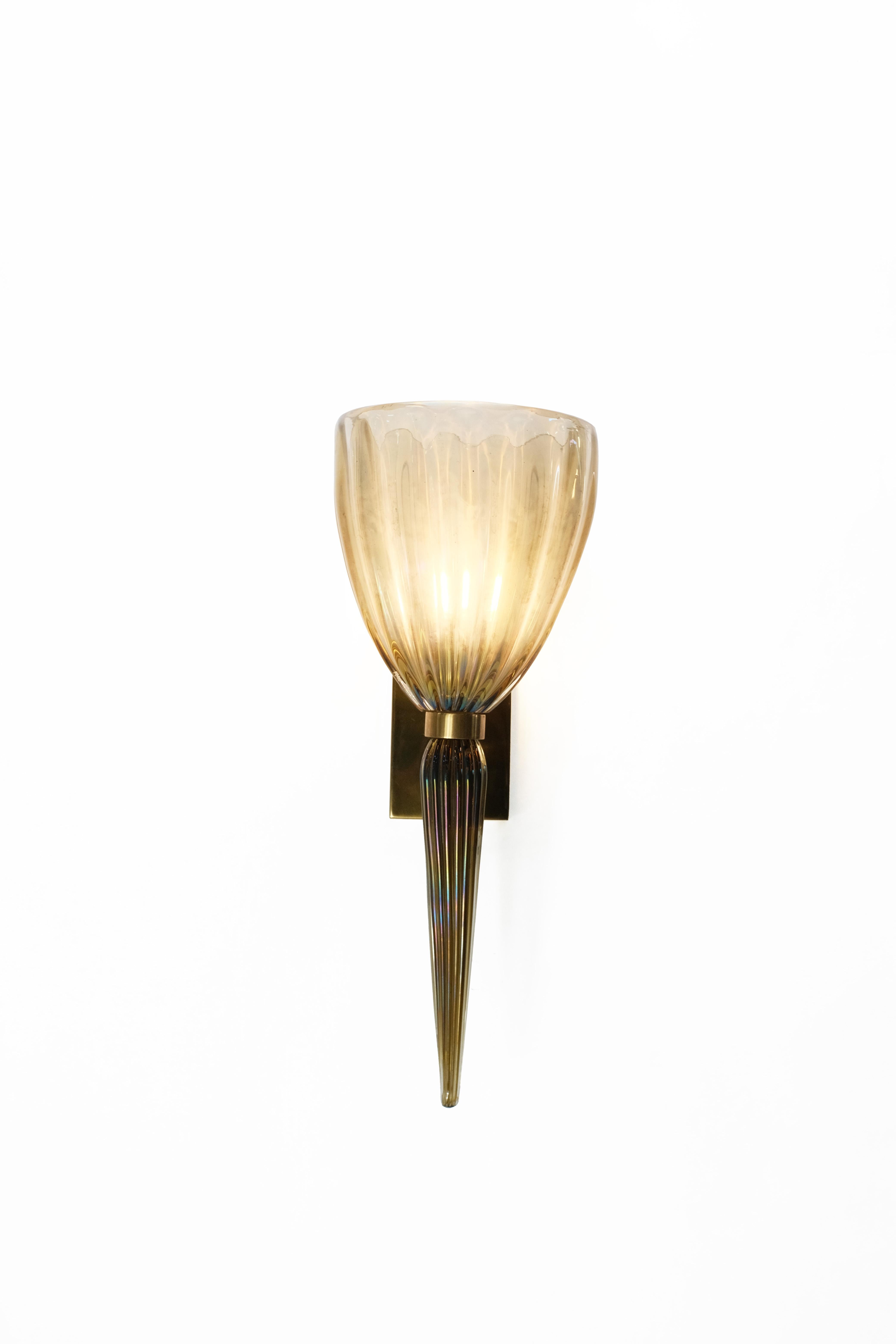 Una fusión atemporal de artesanía italiana y elegancia moderna, este par de apliques de pared vintage de cristal de Murano es el epítome de la iluminación ambiental refinada. Soplado a mano en un cálido tono ámbar, cada aplique presenta un cristal