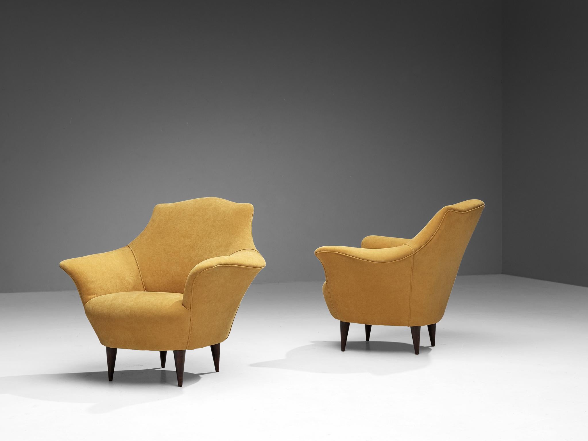 Pair of club chairs, velvet, stained ash, Italy, 1950s.

This lovely pair of Italian lounge chairs is characterized by a sophisticated aesthetic due to its curvaceous lines and round edges. The seating area is supported by sleek outward-facing legs