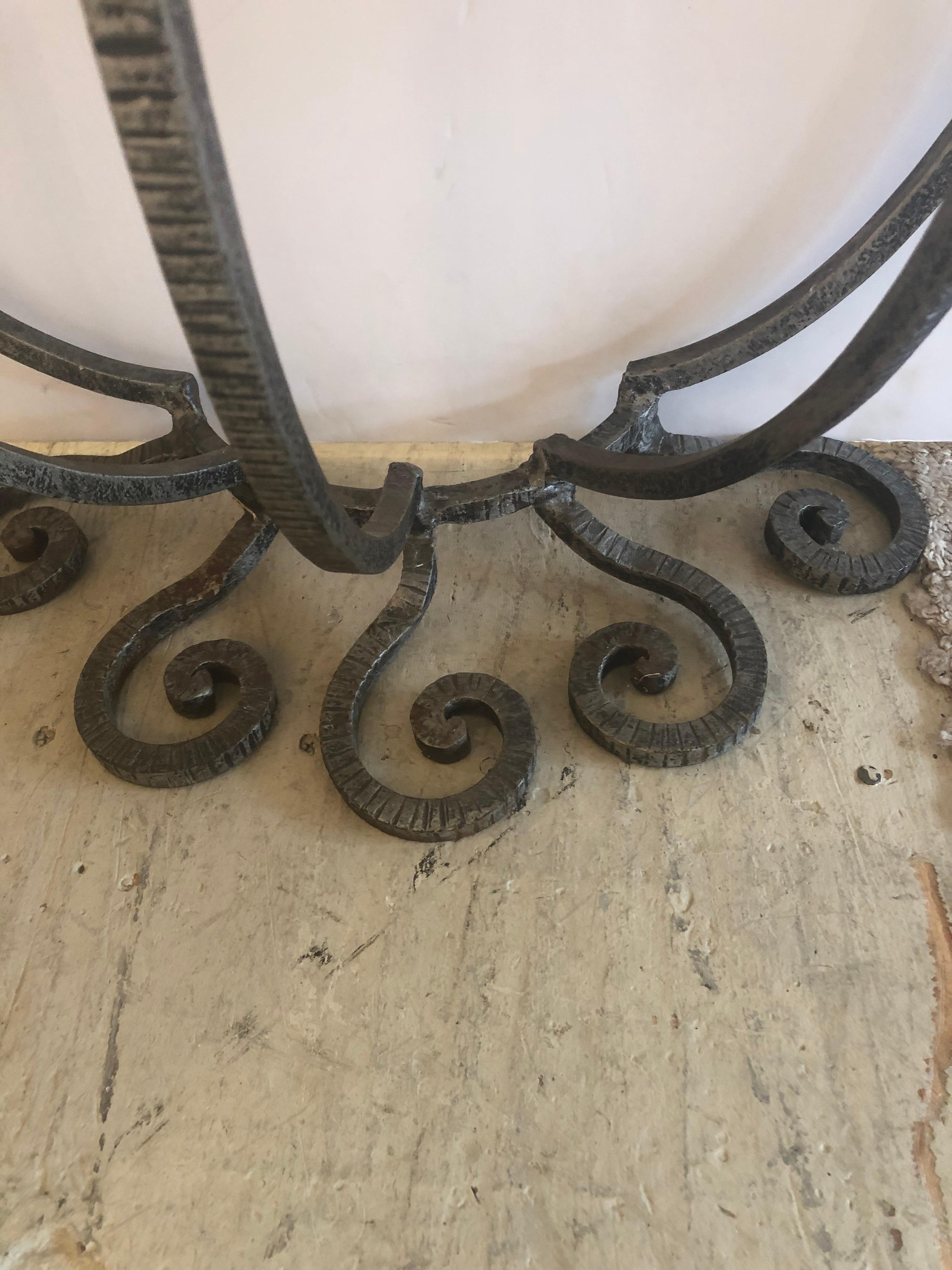 An elegant pair of Salterini style hand forged wrought iron demilune consoles with fabulous curlicues especially on the bases and having black glass tops.
Chip on the back edges of one. Could easily be replaced if desired with glass, mirror or