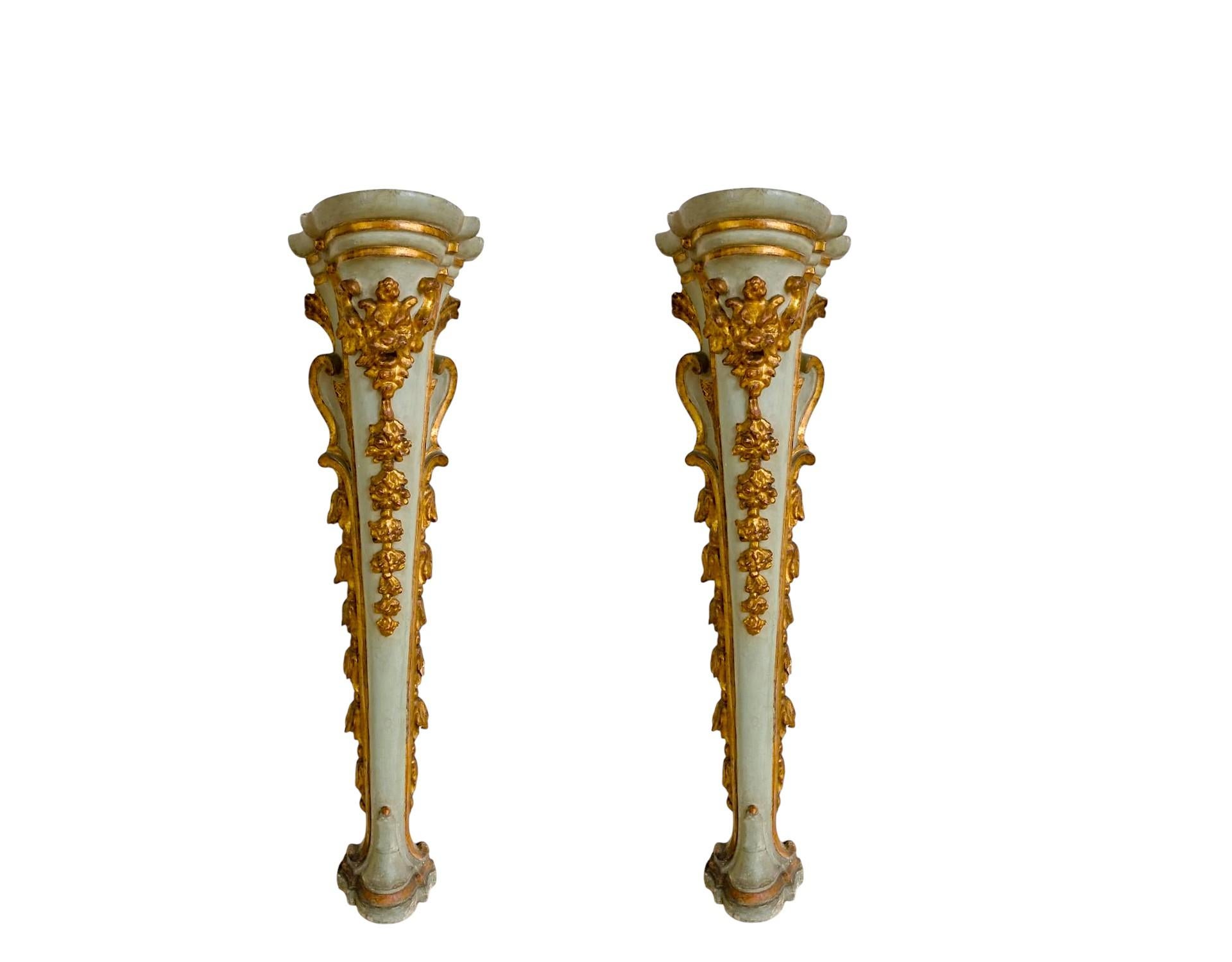 Elegant pair of Louis XV wall columns.

Lacquered and gilded wood with floral carvings and central mask. The lacquered parts of a gray tending to light blue combined with the sculpted and gilded parts contribute to making their slender shape even