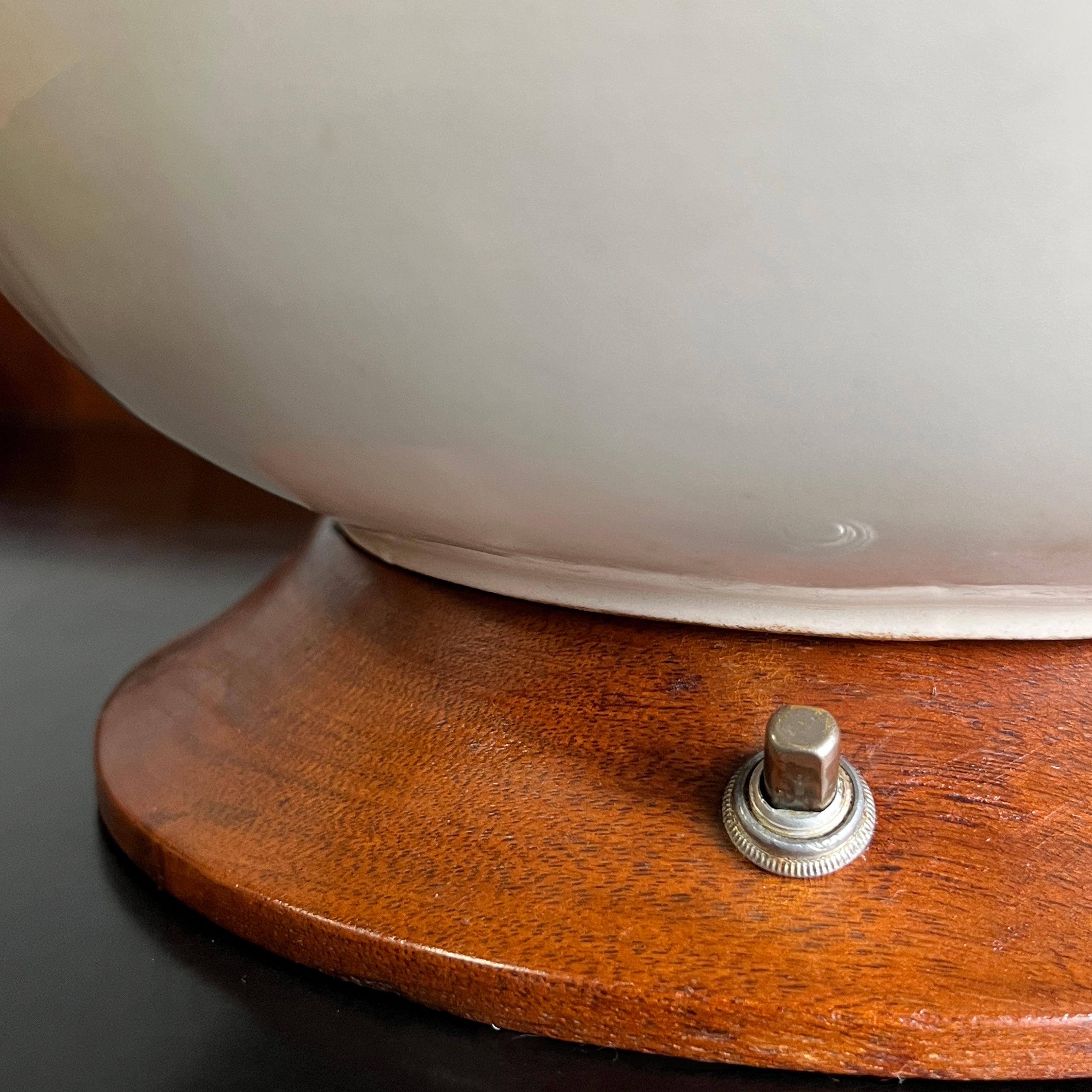 This pair of Mid-Century Modern table lamps features a circular bulbous ceramic body with a white glaze with wonderful crazing. The circular base and neck are made of teak with a warm patinated finish. The lamps are in working condition and wired to