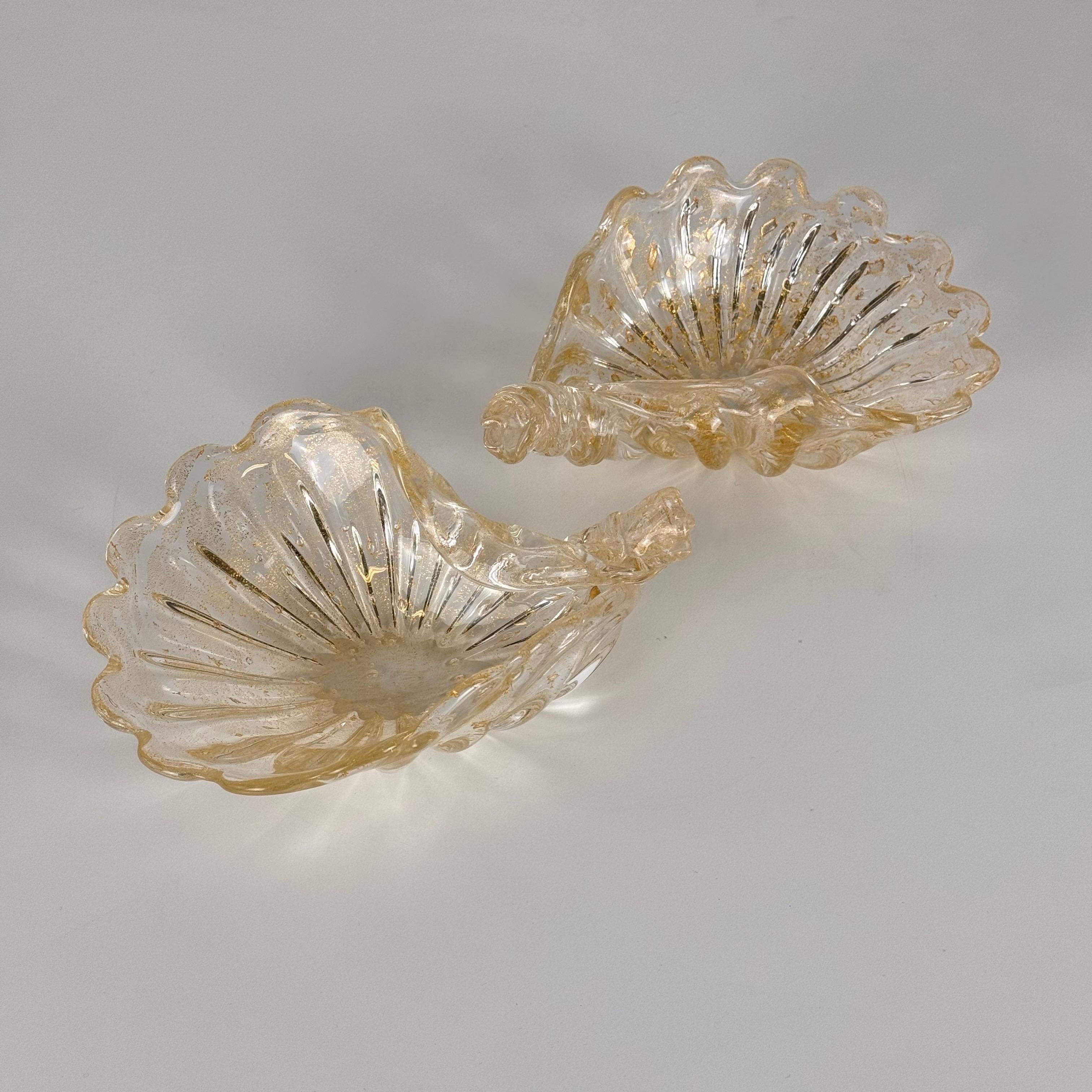 Este excepcional par de colgadores de cristal de Murano, fabricados por la prestigiosa Formia, refleja maravillosamente la elegancia intemporal de la artesanía veneciana de los años setenta. Con forma de delicadas conchas, estas piezas son una