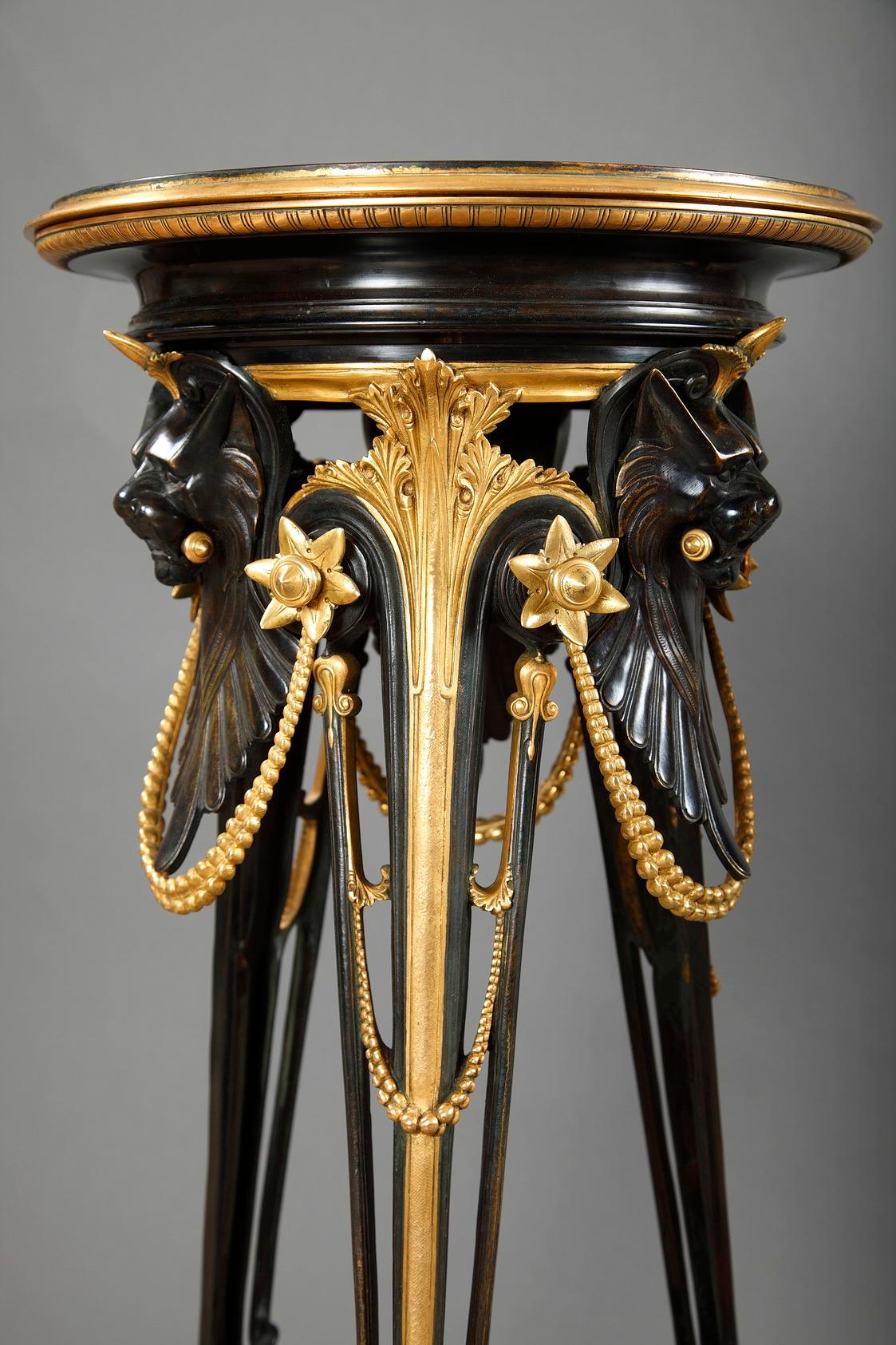 Pair of patinated and gilded bronze high gueridons attributed to G. Servant,. Each of them has three paw feet, headed by stylized lion muzzles, ornated with beaded chains and joined by a fine foliate stretcher. Surmounted with a circular bronze