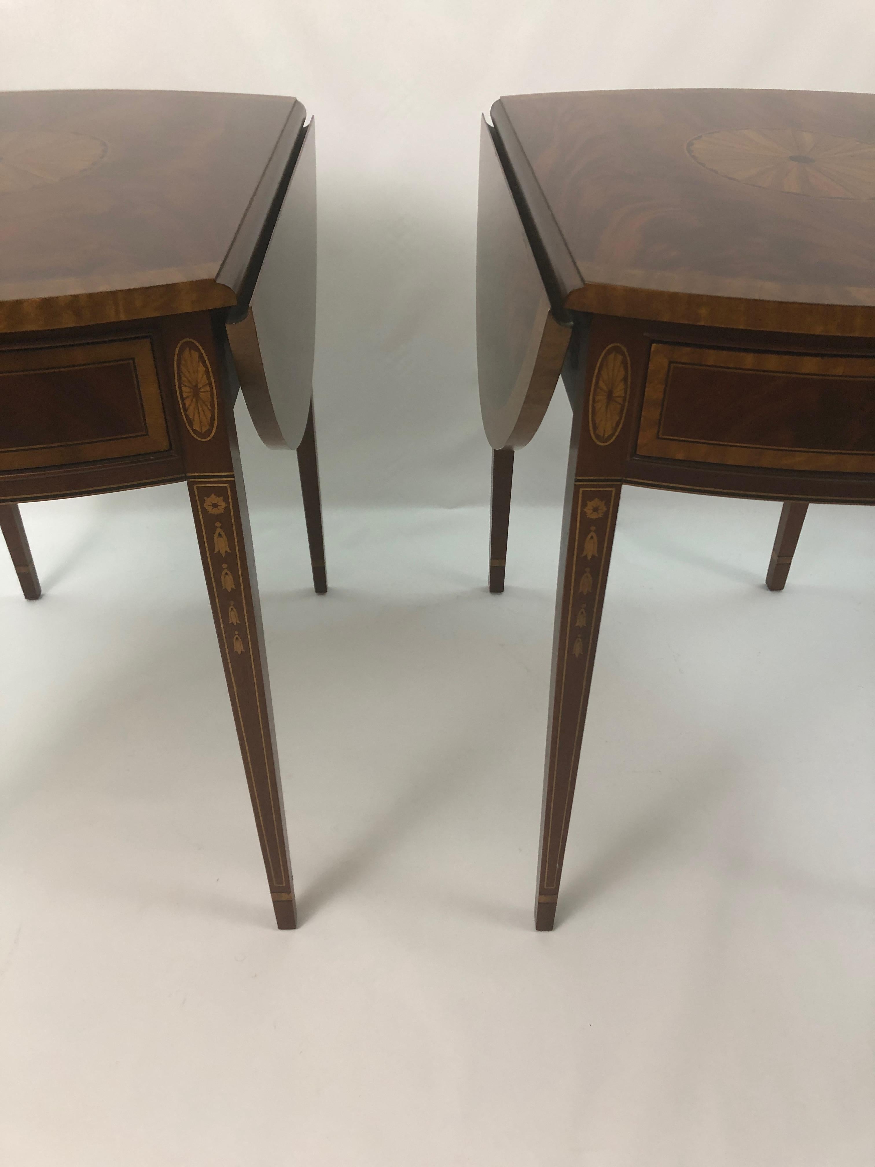 A stately pair of drop-leaf flame mahogany end tables by Councill that are rectangular with the leaves down and 21 W, then round with the leaves extended. Gorgeous mahogany with satinwood and ebony inlay having bell flower accents on the tapered