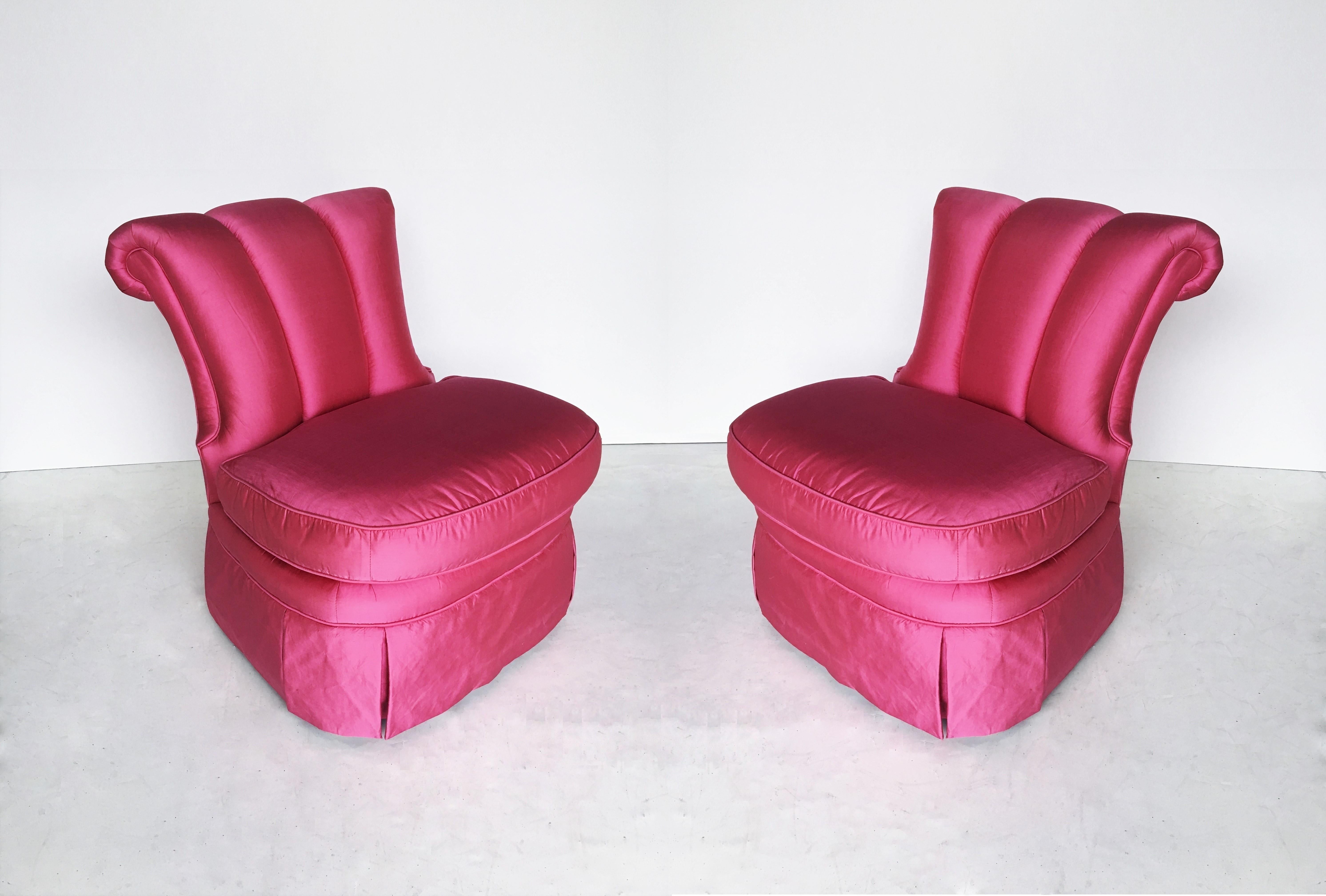 An elegant pair of Regency inspired form slipper chairs. Each chair features channeled back and out scrolled crest rail; the loose seat cushion upholstered in pink silk fabric. They stand on legs covered by a pleated skirt. These are in wonderful