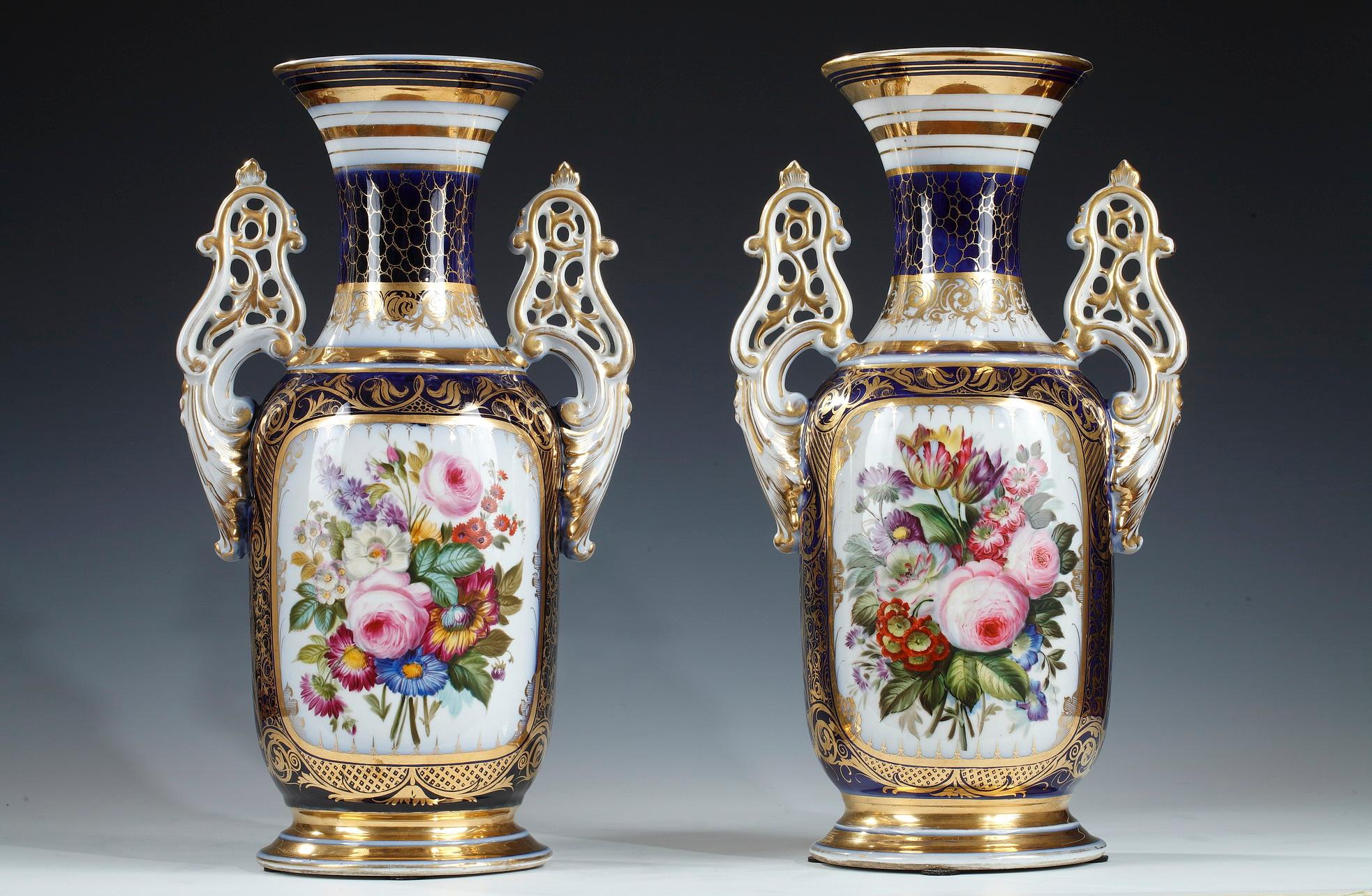 Charming pair of baluster shaped vases made in Valentine porcelain, with openwork handles enhanced with gold. They are decorated on the front with a polychrome bouquet of natural flowers in a cartouche with a golden interlacing frieze, and on the