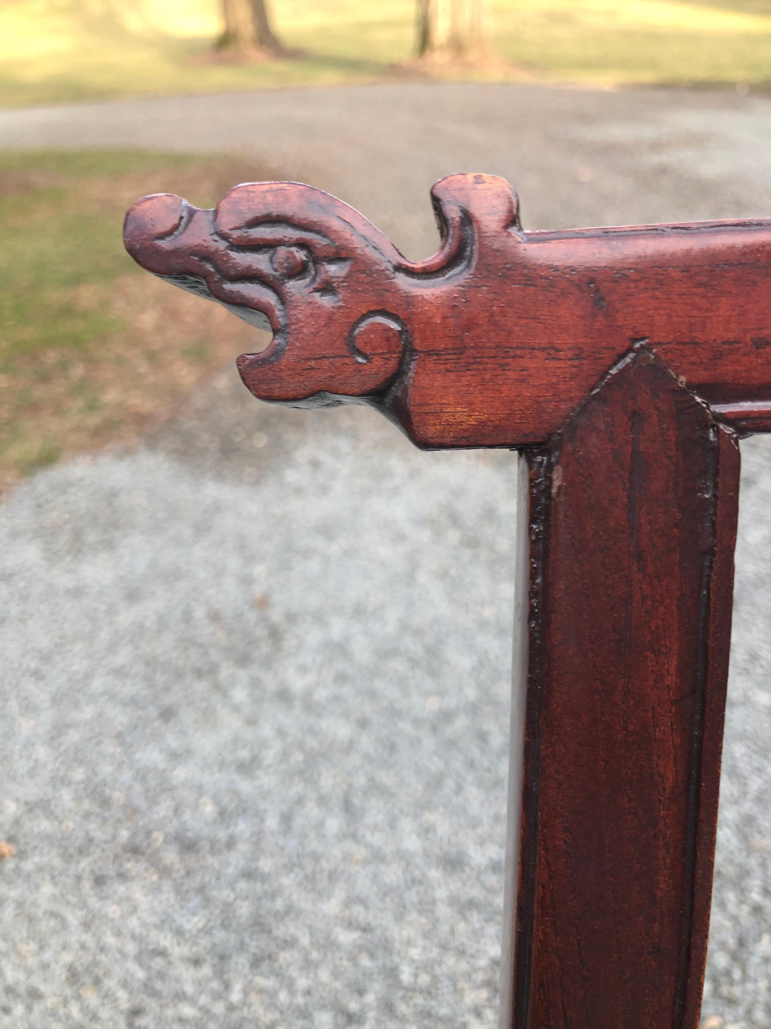 A pair of Asian inspired rosewood accent or side chairs with beautiful rich patina. The corners of the backs of the chairs are decorated with hand carved dragon heads and the back splats have a slight undulation.