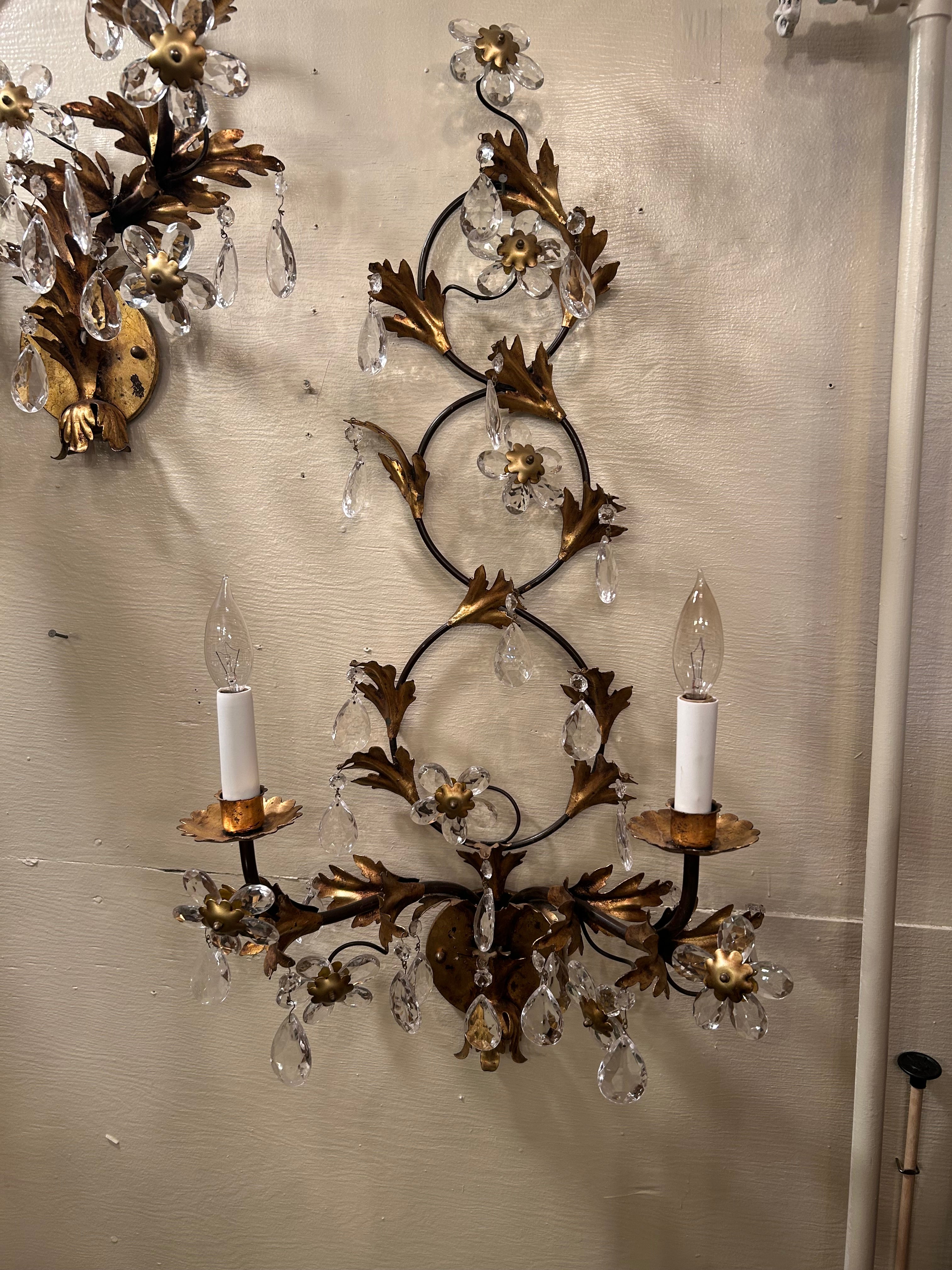 Large elegant pair of giltmetal sconces having two arms, intertwining circular forms adorned with foliage, crystal teardrops and flowers.  Wired and ready.
(Caroline)