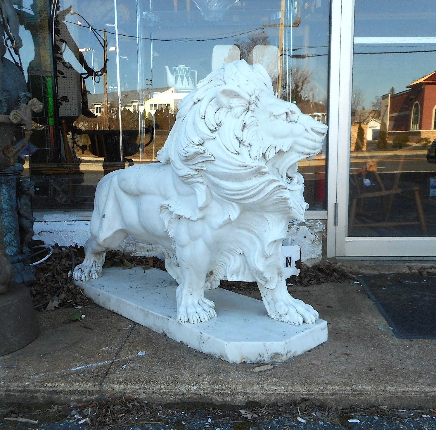 This stunning pair of lion statues are made of solid white marble. These majestic garden ornaments sit on thick marble slabs and feature plenty of hand carved detail. A fierce pose with its mouth wide open and a flowing mane shows tons of