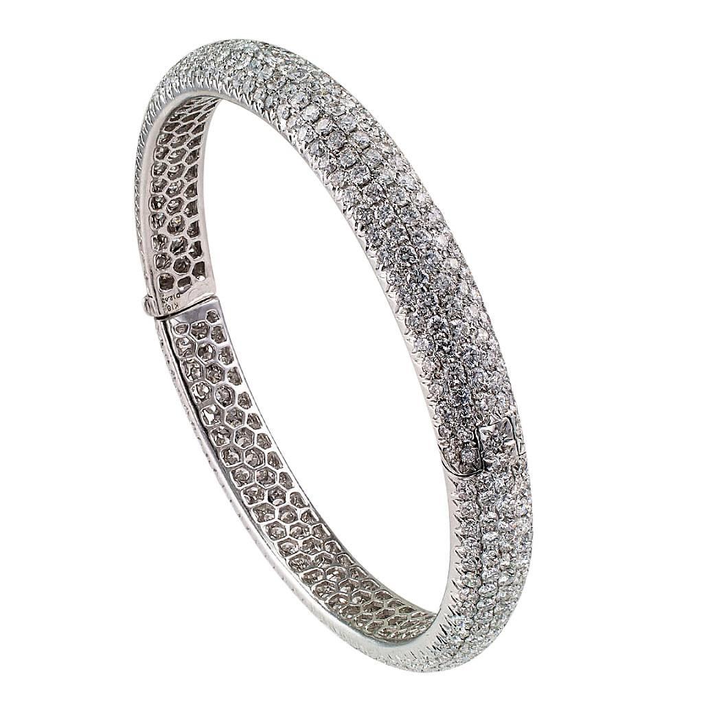 Estate diamond and white gold bangle bracelet. A contemporary hinged bangle bracelet continuously pave-set with four hundred sixty-seven round brilliant-cut diamonds totaling approximately 12.63 carats, approximately G - H color and VS clarity,