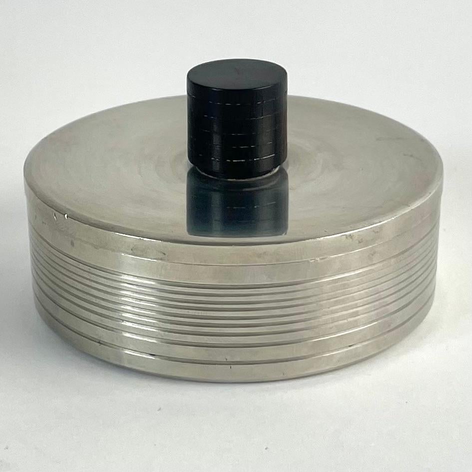 Elegant Pewter Box with Black Wooden Knob, GAB 1934

An elegant round pewter lidded box by GAB (Guldsmedsaktiebolaget), Sweden, made in 1934 (date letter H4). The box features a finely ridged surface and a black-stained wooden knob with turned rings