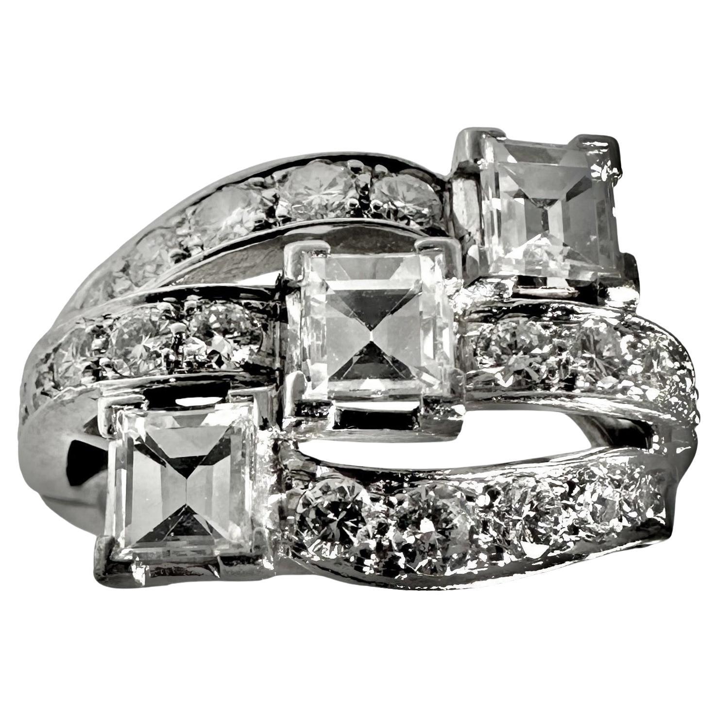 This platinum and diamond, original Art-Deco period cocktail ring, is uniquely styled, and features three mirror cut emerald cut diamonds accented with round brilliant cut diamonds. The manner in which the emerald cuts are placed creates a great