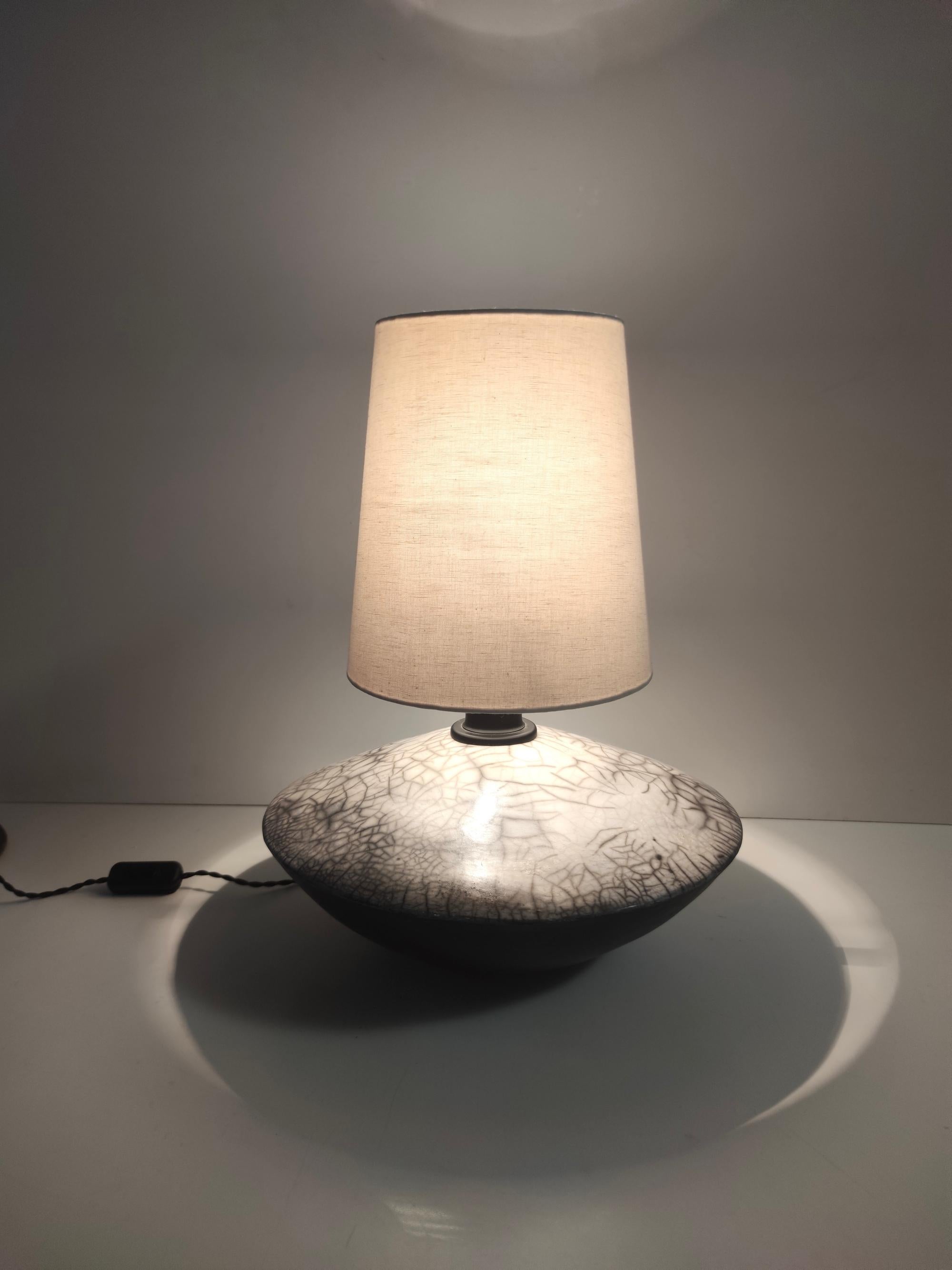 Made in Italy, 1980s.
It is signed but the signature is not comprehensible.
The lamp features an handmade rake ceramic base and a fabric lampshade.
The wiring has been inspected and is compatible with the US. 
It might show slight traces of use