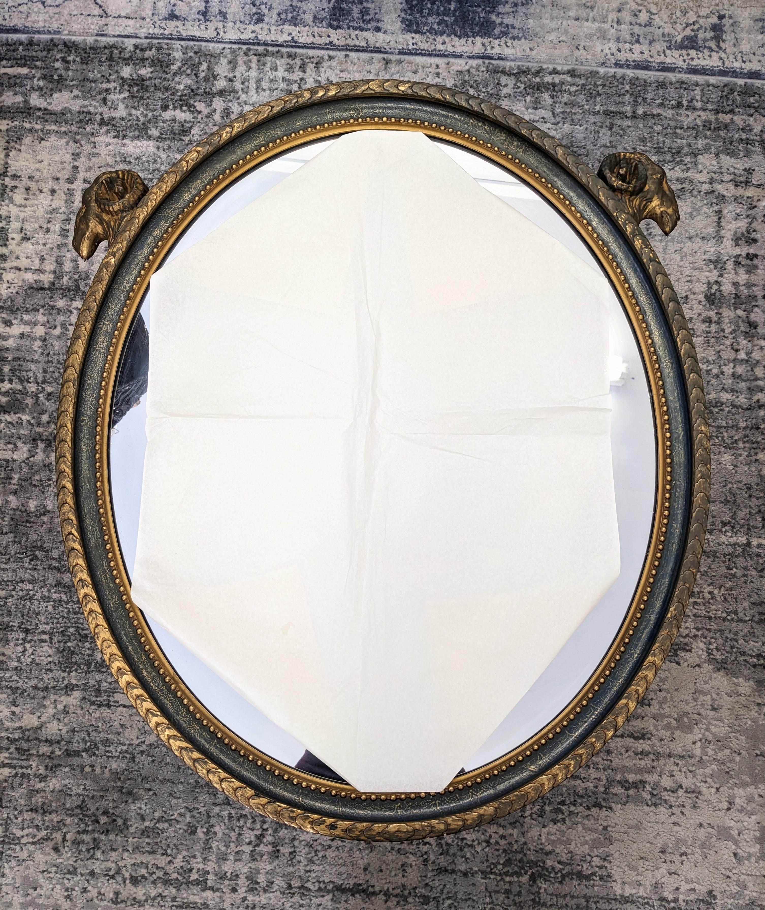 Eleganter ovaler Spiegel mit Widderkopfmotiv aus den 1920er Jahren im neoklassischen Stil mit antiker Gold- und tiefblauer Patina. Schöne ovale Form mit neoklassizistischen Verzierungen. Maße 32
