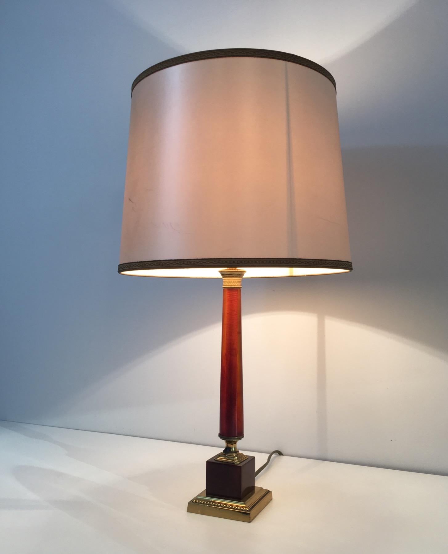 Cette élégante lampe de table néoclassique est composée de deux rares parties en celluloïd rouge séparées par du laiton. Il s'agit d'une œuvre française, vers 1950.
