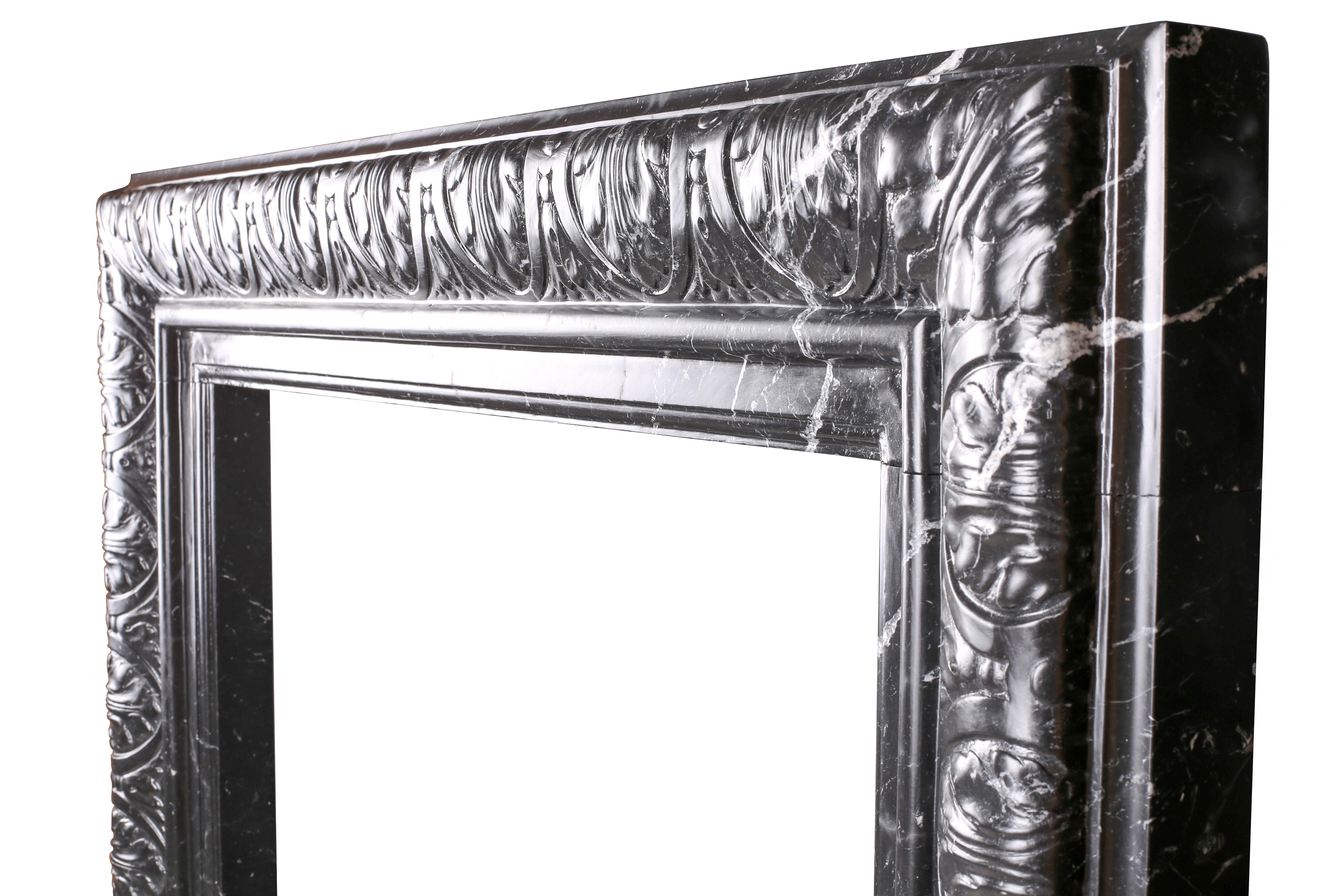 An elegant Regency Baroque carved bolection fireplace surround in high quality Italian nicely veined Italian Nero Marquina marble.

Measures: Depth 4 1/2 in (115mm) 
External height 45 3/4 in (1162mm)
External width 54 in (1370mm)
Internal