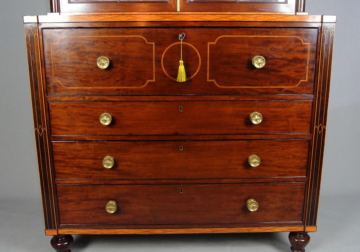 Una libreria secretaire di grande effetto e qualità, con intarsi in legno di raso ed ebano sul mogano ben figurato.   Alto ed elegante, non è stato risparmiato alcun dettaglio o costo nella sua costruzione e il piano della libreria presenta un
