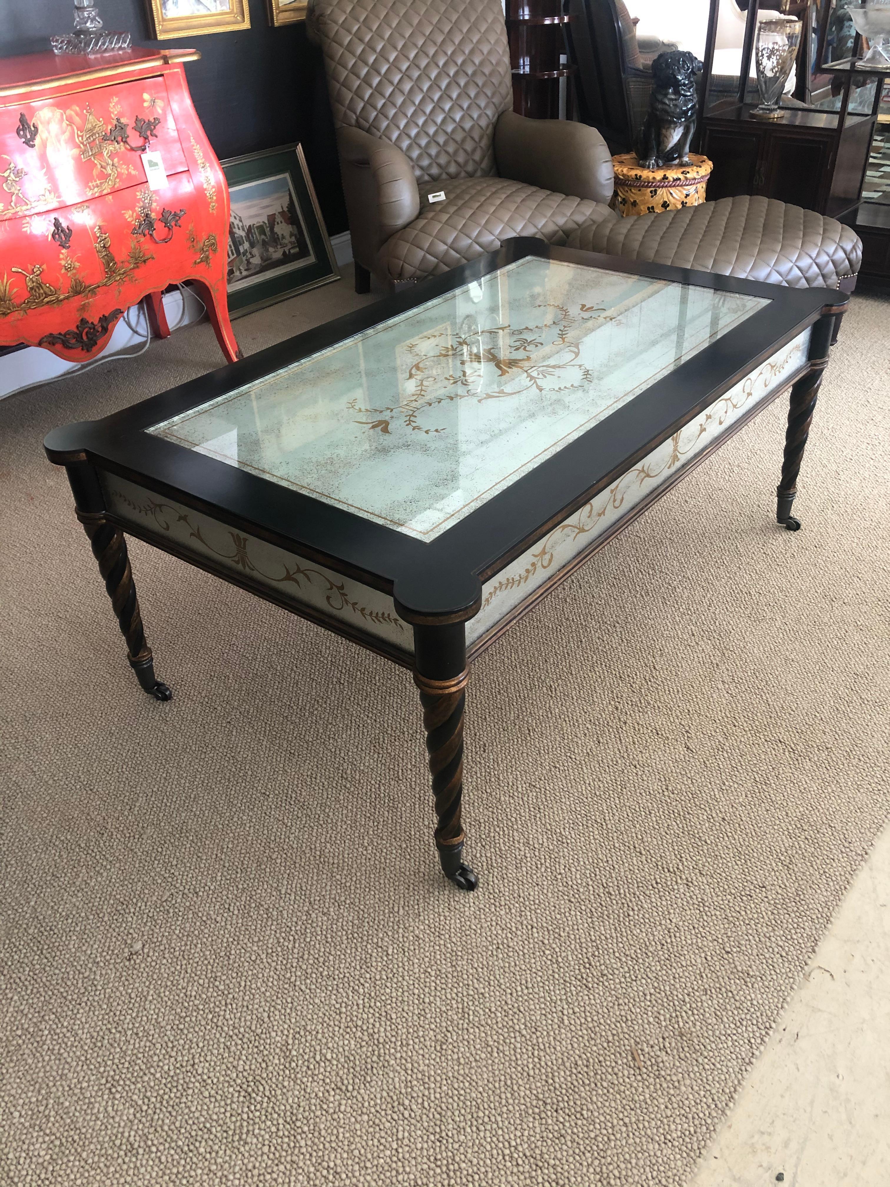Impressive designer coffee table having ebonized base with twisted tapered legs and gorgeous églomisé mirrored inset top and sides. Legs also have gilded bronze embellishments and terminate in brass casters.
