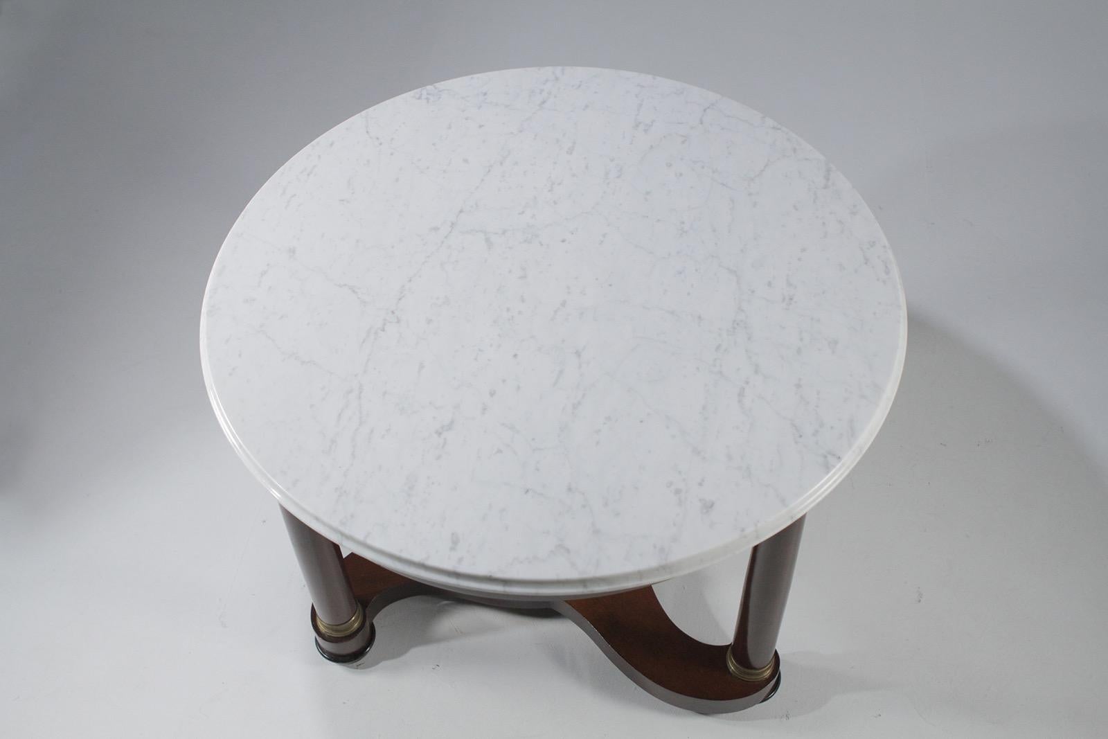 Stately round Regency style center table having a handsome mahogany base with 3 sided stretcher between the ebonized tripod legs, a beautiful white marble top, and bronze decorative mounts.
