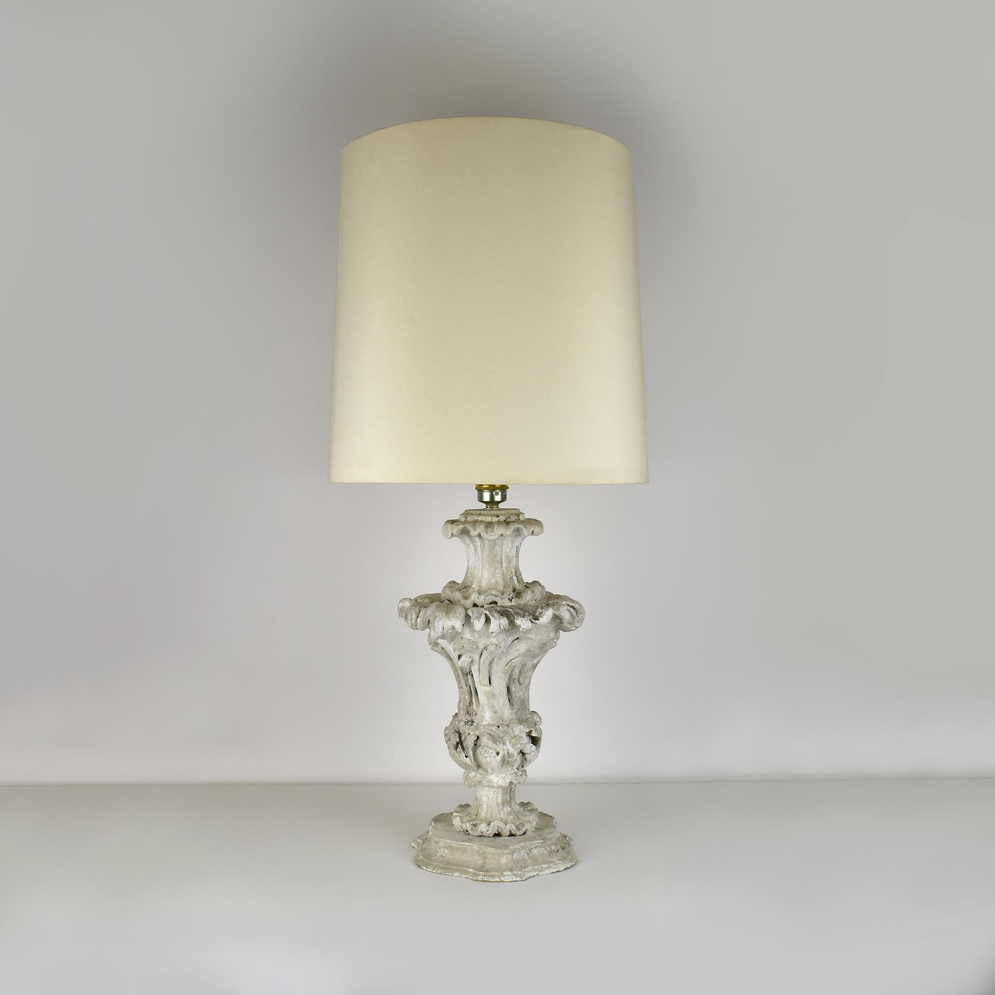 This exquisite table lamp, constructed from plaster over a wooden core, is a stunning example of Rocaille design, a style characterized by intricate ornamentation and organic forms. The lamp features a beautifully sculpted body adorned with delicate