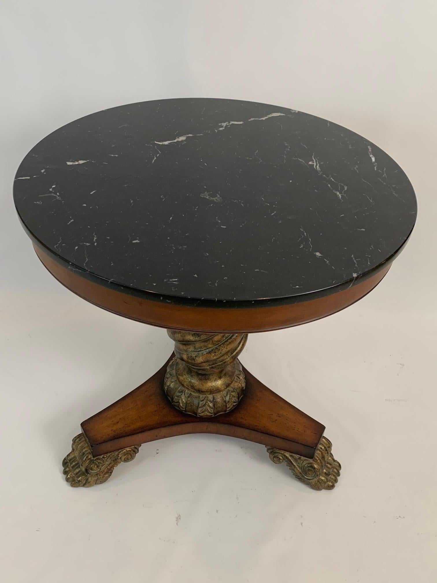 Very elegant Hollywood Regency style side table having marvelous contrasting black marble top offset by rich fruitwood base with carved faux painted gilded details and handsome paw feet.


 