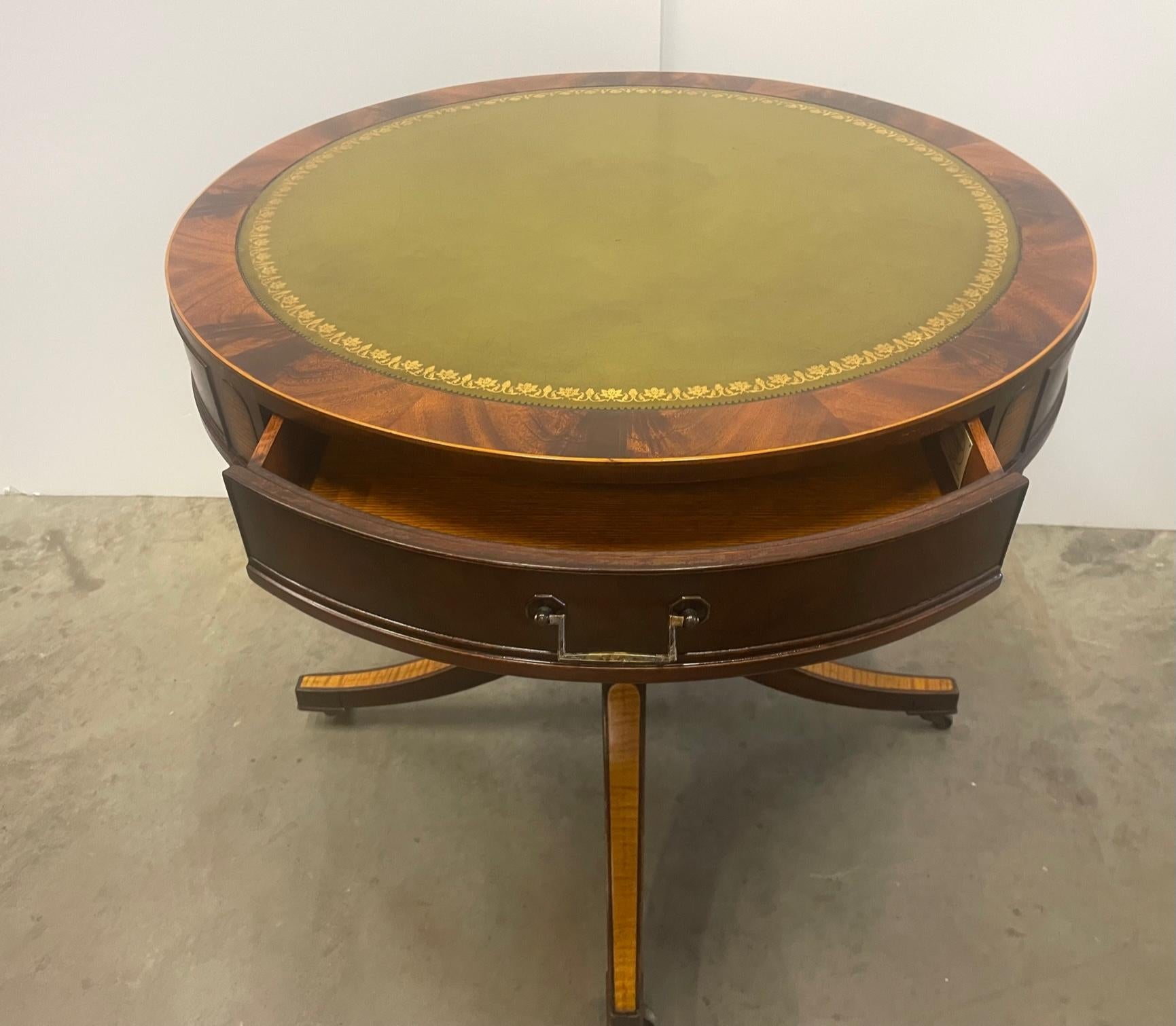 Clásica mesa auxiliar redonda de caoba flameada con preciosas incrustaciones de madera satinada, llamativo tablero de cuero labrado en verde manzana y un solo cajón. Por Hathaways NYC.