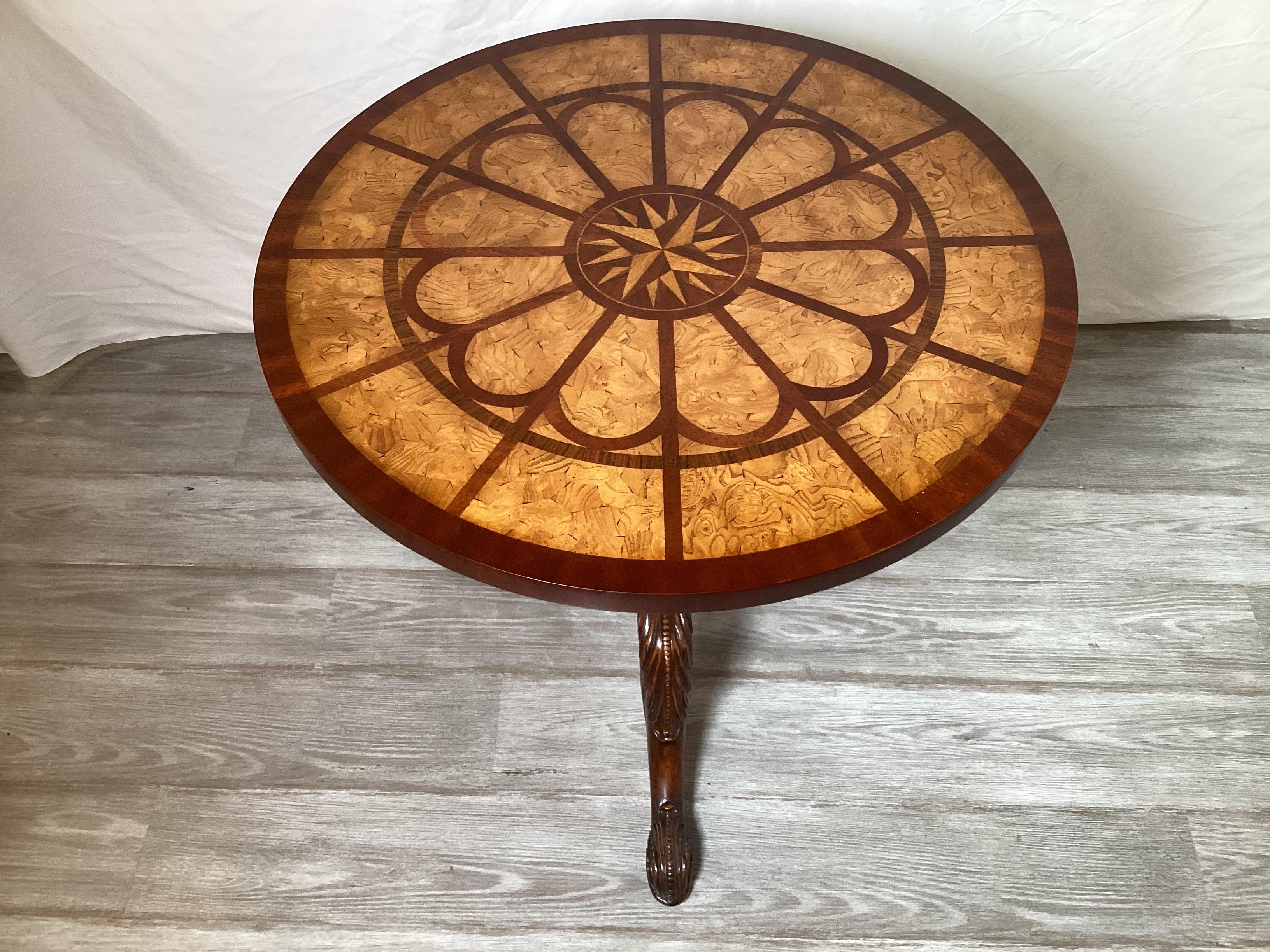 Ein runder Beistelltisch aus Mahagoni und Satinholz mit Intarsien von Maitland Smith.  Die runde Platte mit aufwändiger Intarsie mit zentralem Starburst.  Der Sockel mit Mittelsäule mit Handschnitzerei mit schön geschnitzten Beinen.  26 Zoll im