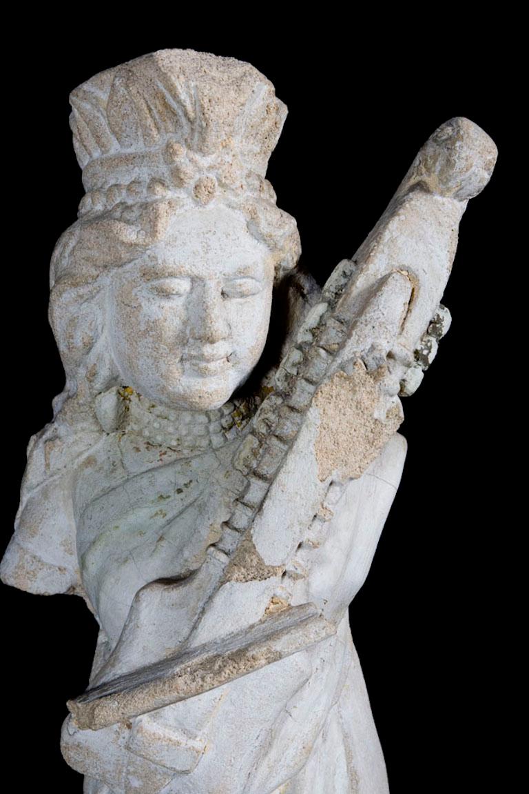 Elegante Sandsteinskulptur einer Sitar spielenden Apsara mit fehlenden Armen, schönem Gesicht, hohem Diadem und plissiertem Gewand. Er wird mit einem speziell angefertigten Sockel aus Lucite geliefert.

Gewicht: 21,3 lbs
Abmessungen: 7.5 T x 10 B