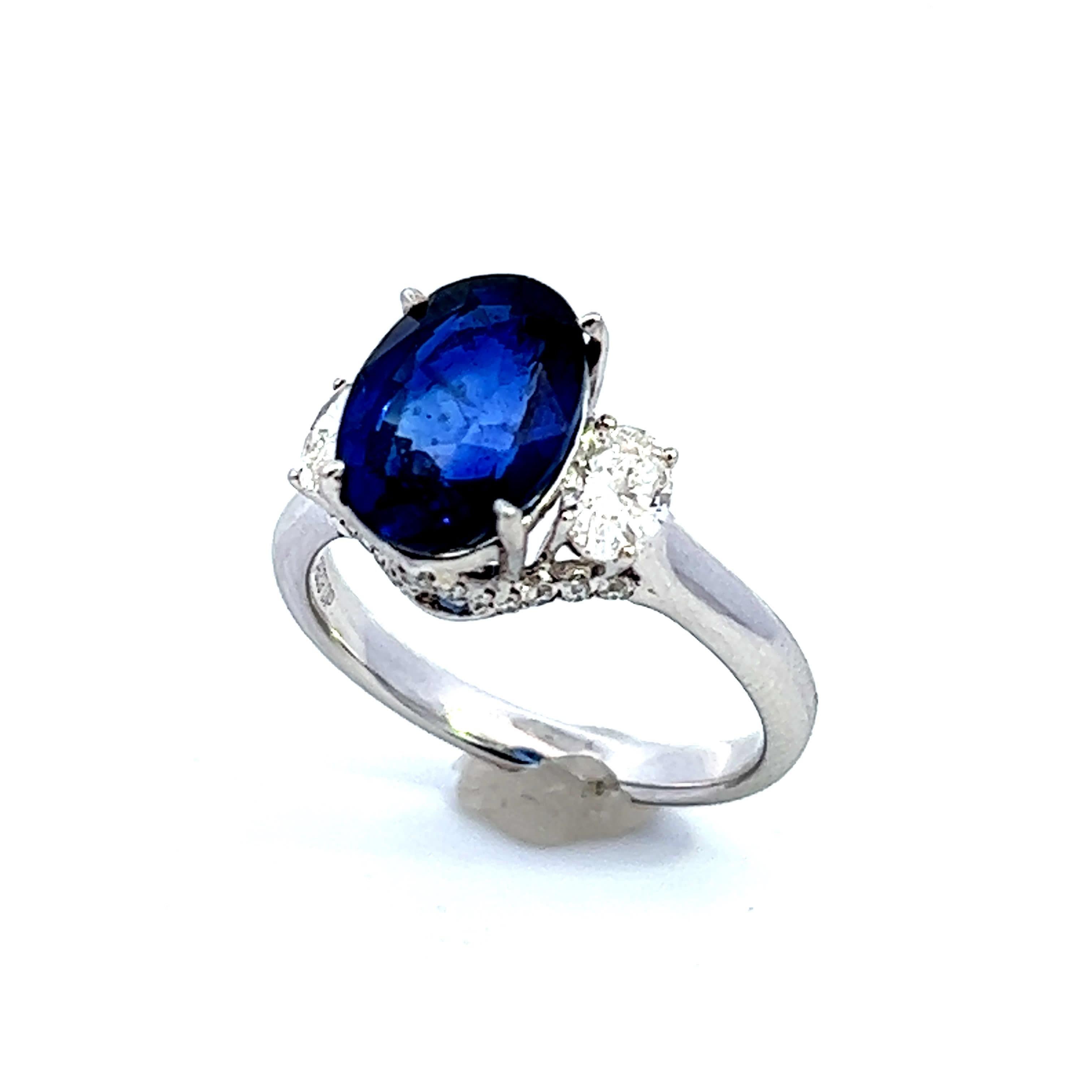 Entdecken Sie die Anziehungskraft dieses atemberaubenden Rings mit einem ovalen Saphir und Diamanten in der Mitte. Der satte Blauton des Saphirs wird durch die funkelnden Diamanten auf beiden Seiten wunderbar ergänzt und schafft ein perfektes