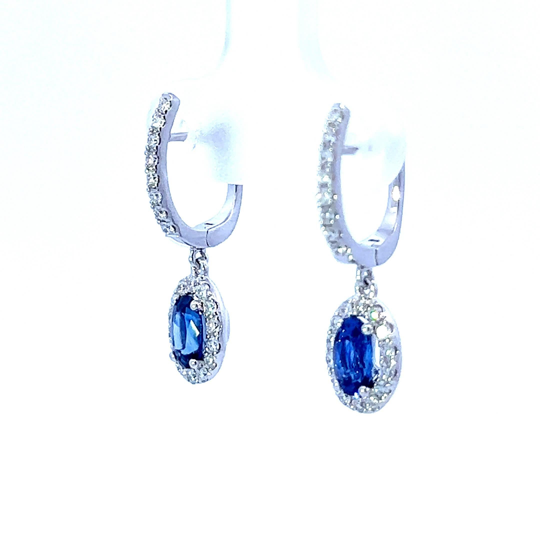 These stunning sapphire drop earrings are the perfect accessory for any occasion. Crafted with exquisite detail, each earring features a vibrant oval sapphire surrounded by a halo of sparkling diamonds, creating a captivating contrast that catches