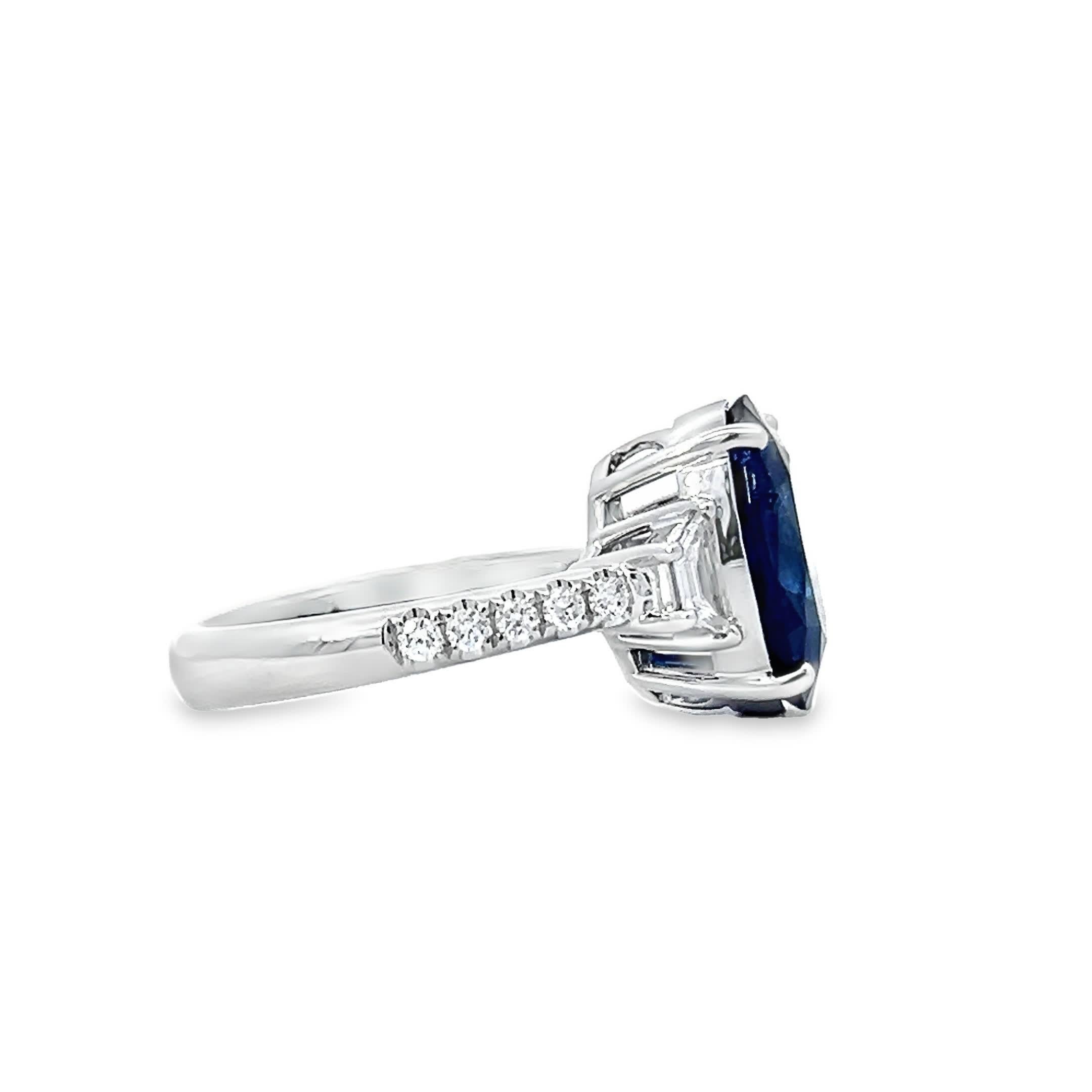 This stunning ring features a deep blue oval sapphire set in a polished white gold band. Flanked by shimmering baguette diamonds, the sapphire commands attention with its rich color and timeless elegance. Perfect for special occasions or as an