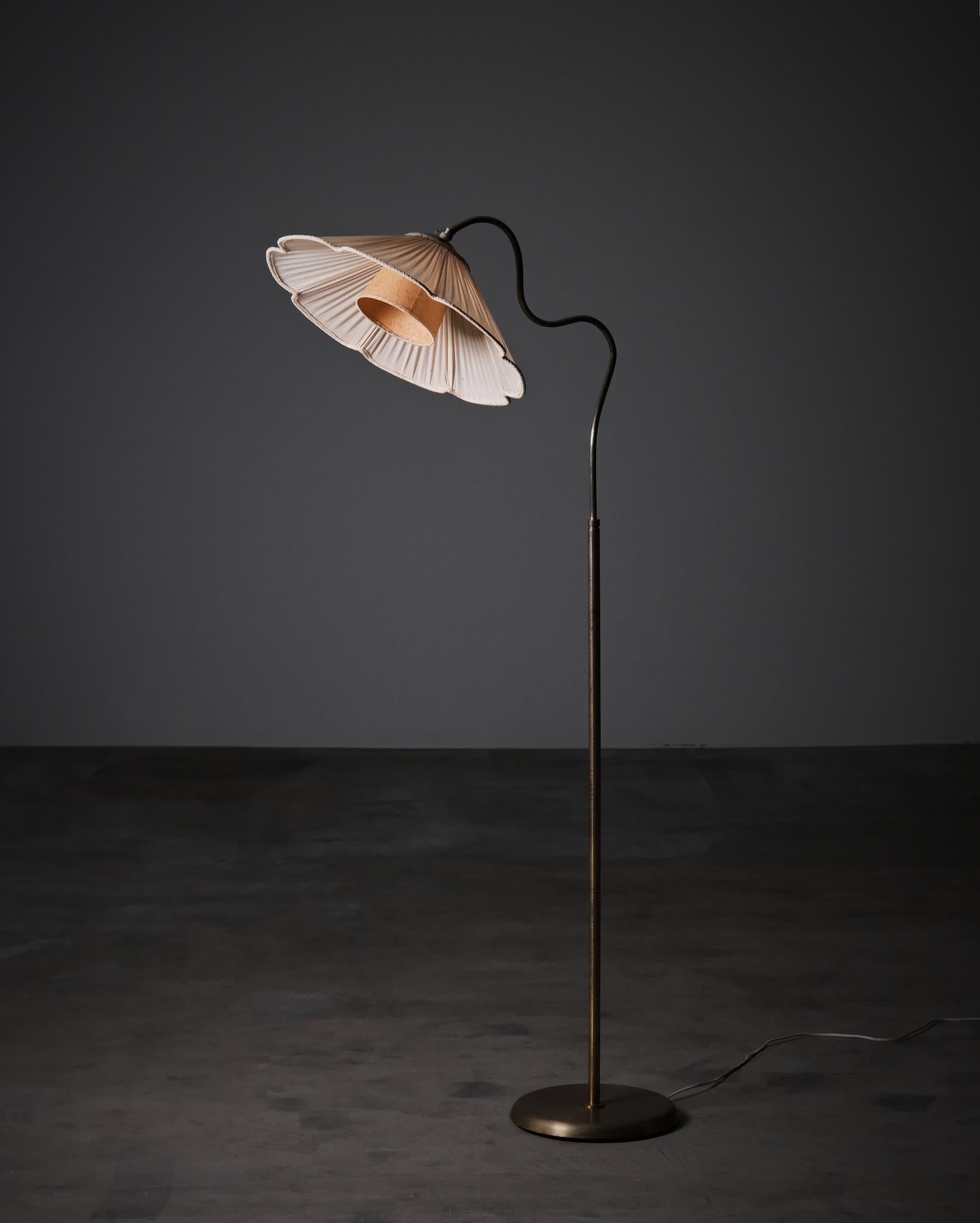 Lampada da terra svedese moderna della metà del XX secolo, designer e produttore sconosciuti. Realizzato in ottone con un paralume delicatamente plissettato, il pezzo presenta uno stelo organicamente curvo che gli conferisce una presenza morbida e