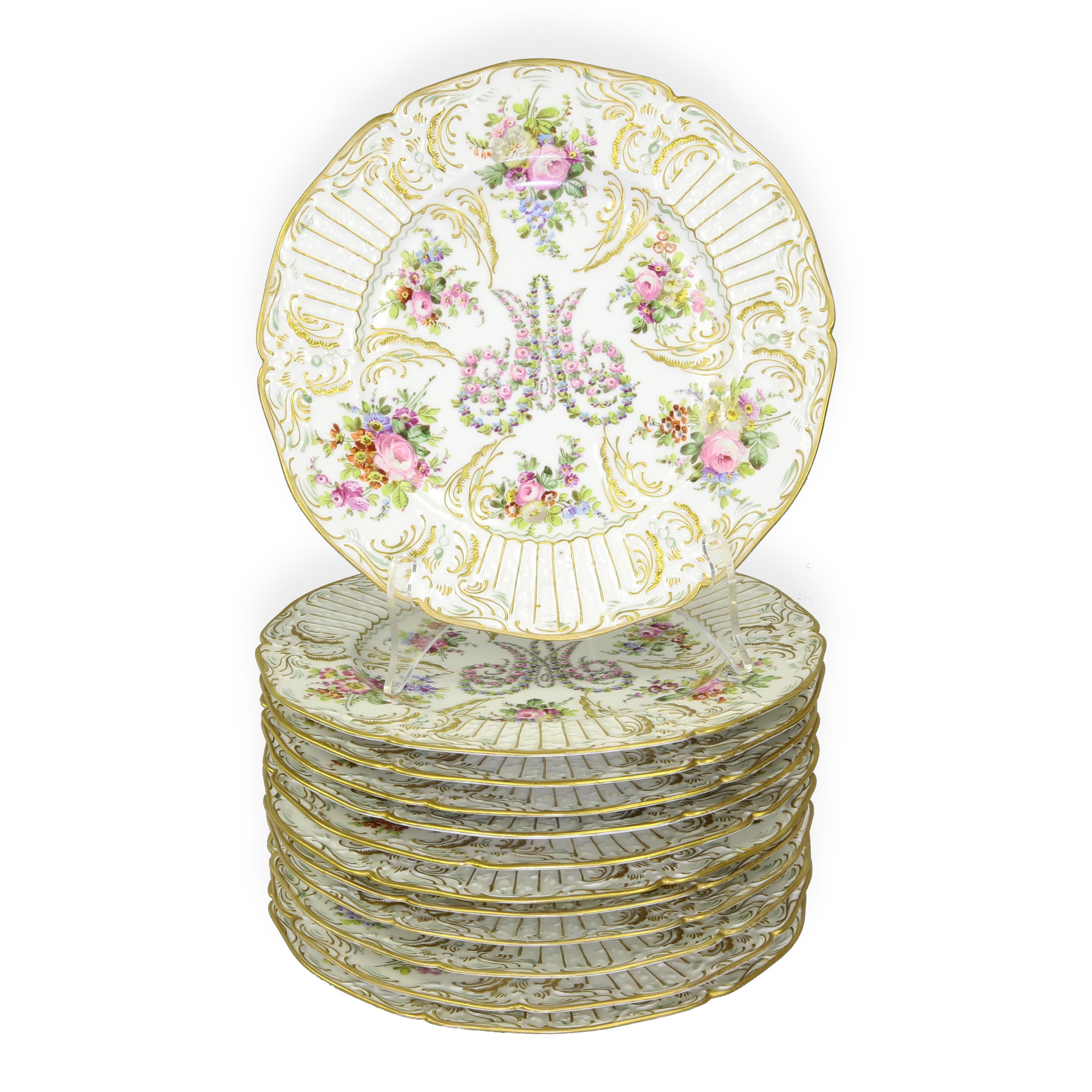 Luxurious antique French porcelain service dinner plates, artfully decorated with beautiful lavish hand painted raised flowers and raised gilt scalloped borders, centring a decorative stylized M. So reminiscent of a springtime garden! Each plate