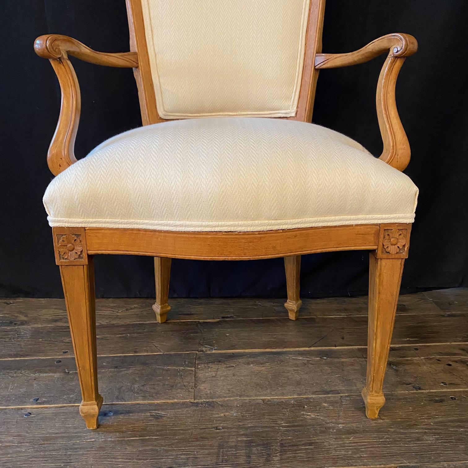 Superb pair of antique Louis XVI style dining armchairs. These lovely carved walnut chairs are in remarkably good solid condition while retaining their original wood surface. The chairs have been reupholstered in a neutral high end linen cotton