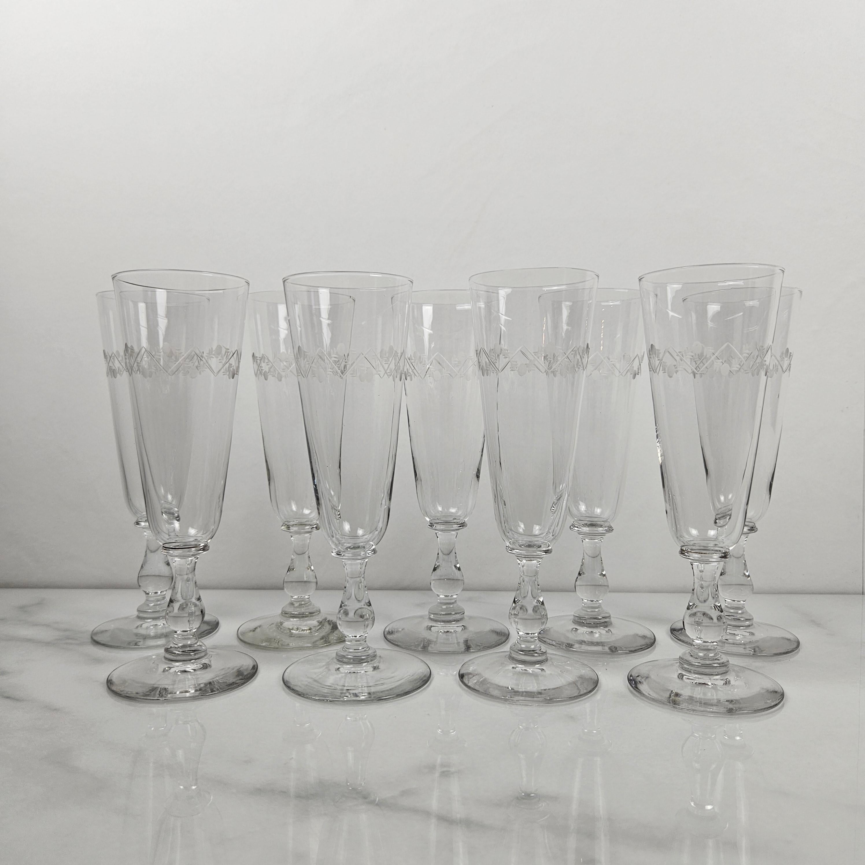 Ce superbe ensemble de neuf flûtes à champagne françaises anciennes met magnifiquement en valeur l'artisanat de la fin du XIXe siècle. 
Chaque flûte est soufflée à la main en cristal clair et présente une décoration gravée exquise autour du bol,