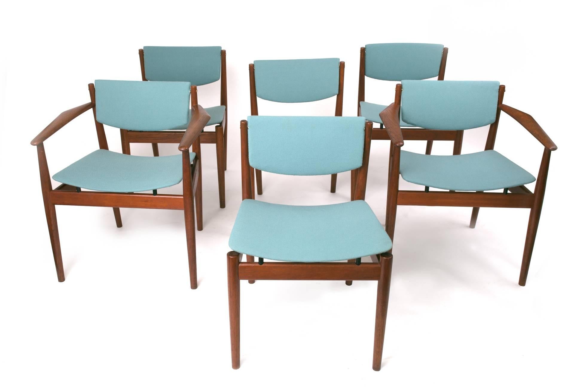 A set of six airy, elegant model 197 dining chairs by Finn Juhl for France & Son. The set includes four side chairs and, uncommonly, a rare pair of armchairs with triangular armrests that embrace the form of the human body. In teak with beautifully