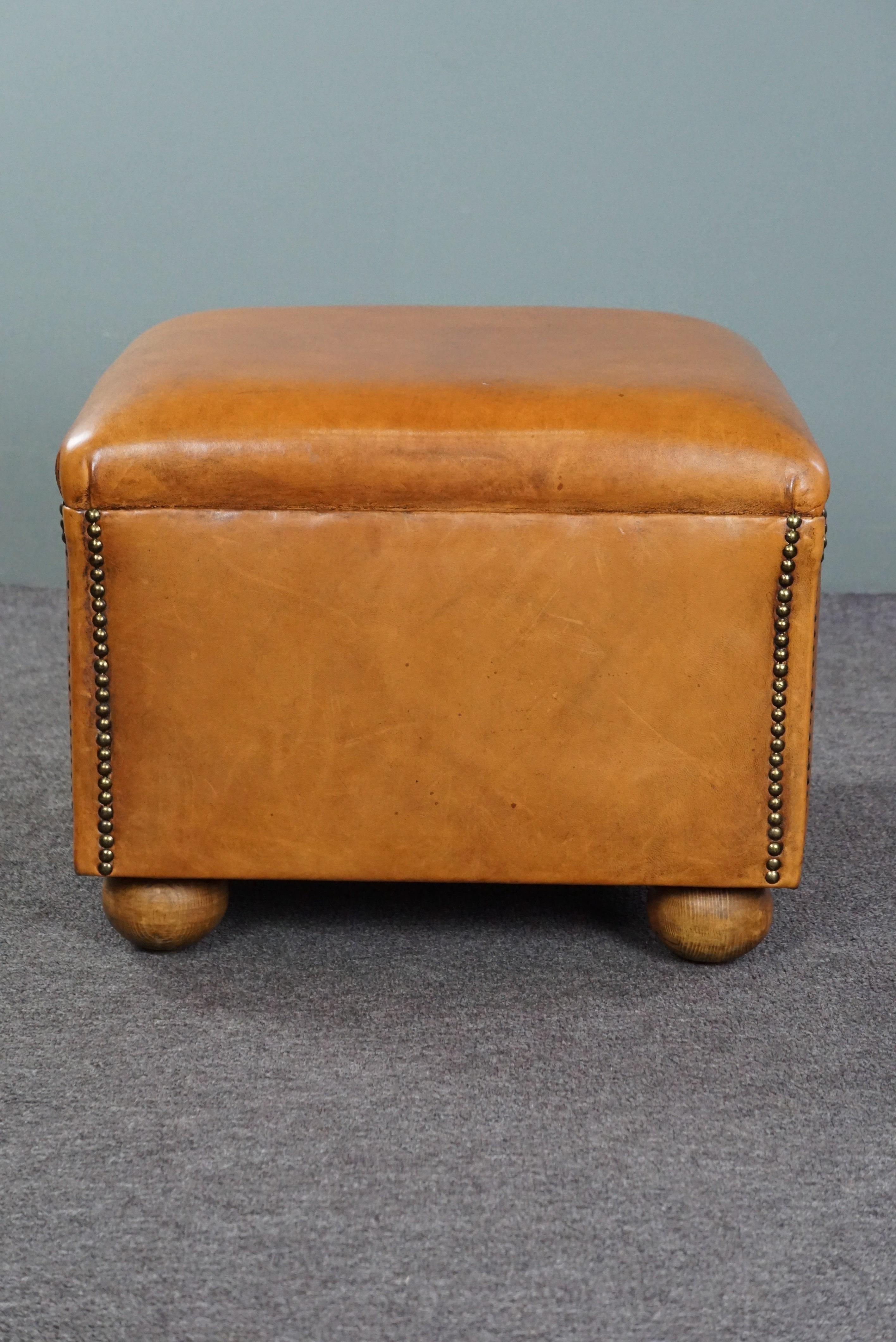 Offered is this beautiful sheep leather ottoman with spherical legs. A sheep leather footstool, also known as an ottoman, transforms your already comfortable armchair into a true relaxation paradise. Resting your feet on this ottoman allows you to